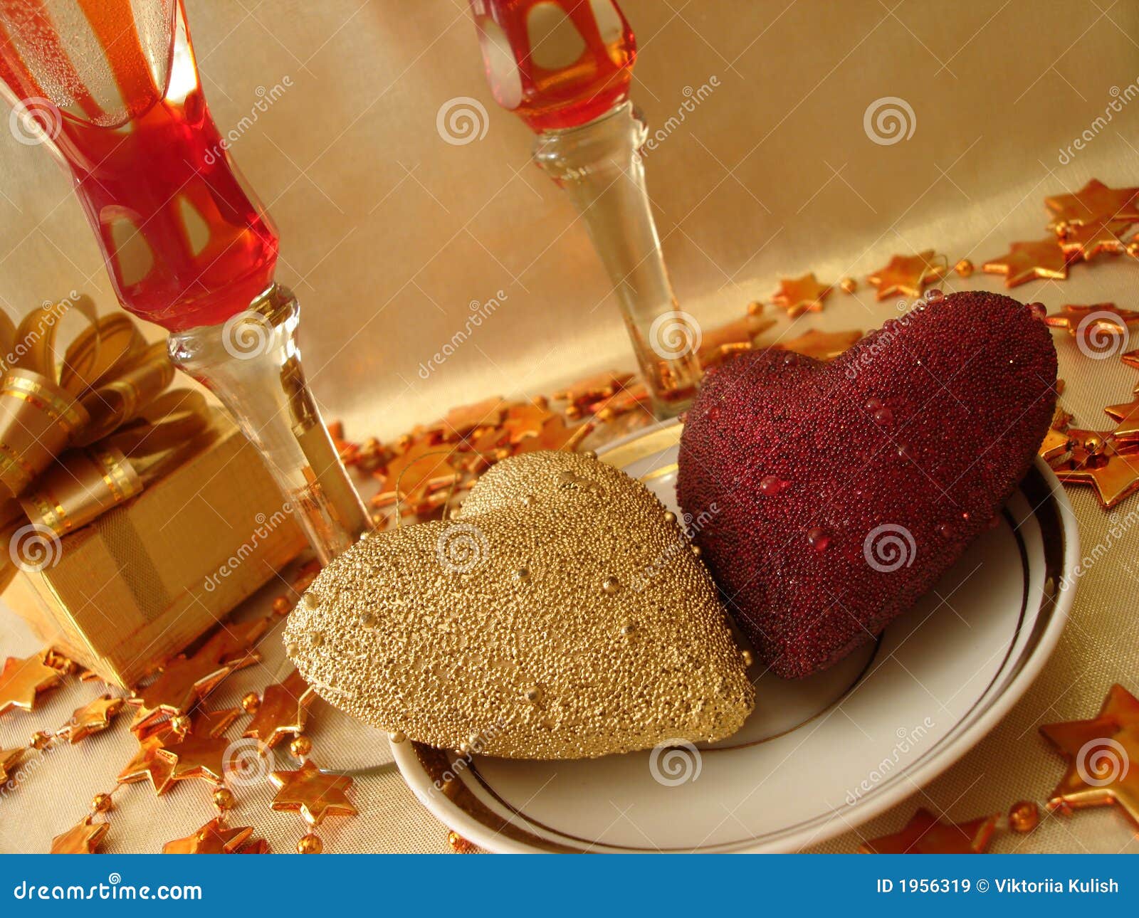 golden and red hearts, gift box and glasses on celebratory table