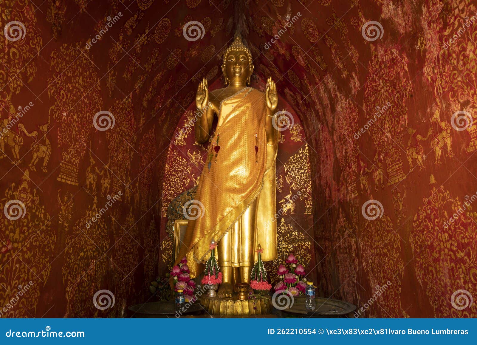 golden statue of a standing buddha in wat xieng thong temple in luang prabang, laos