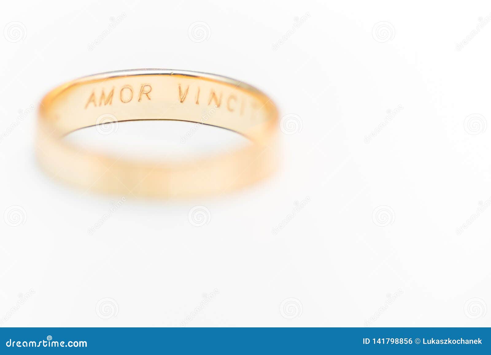 golden wedding ring  on white - amor vincit omnia engraved