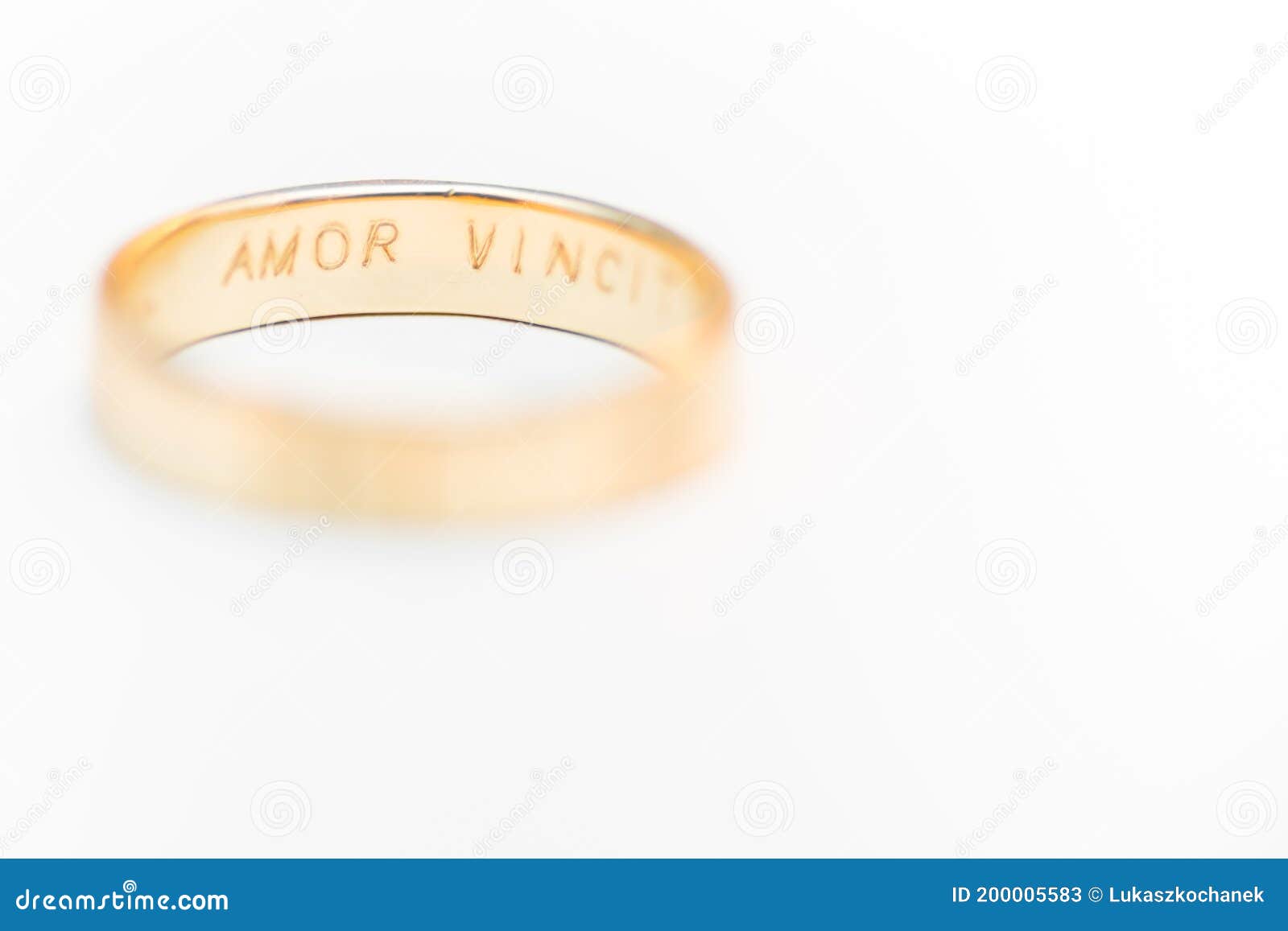 golden wedding ring  on white background - amor vincit omnia engraved