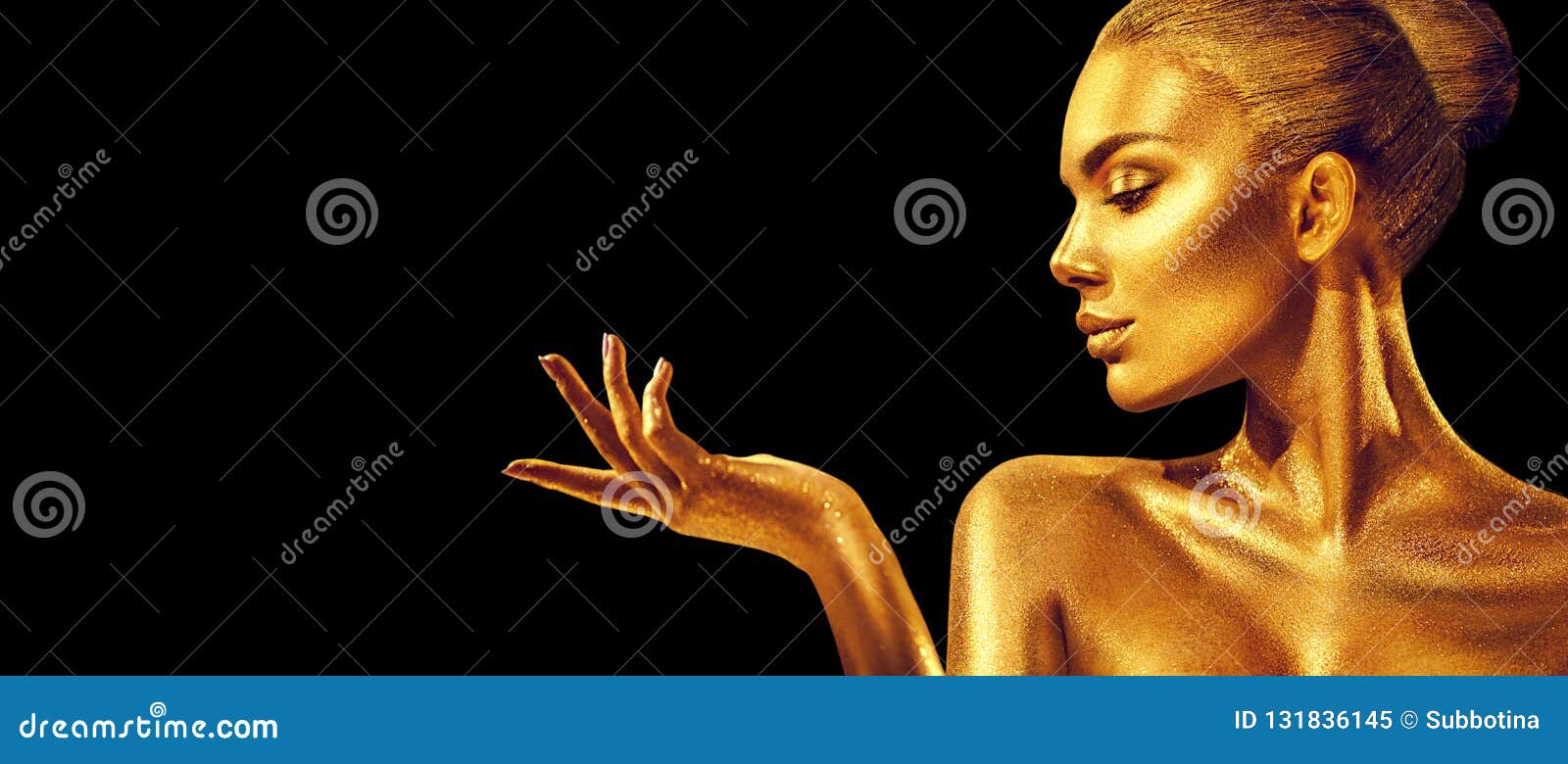 Golden woman. Beauty fashion model girl with golden skin, makeup, hair and jewellery on black background