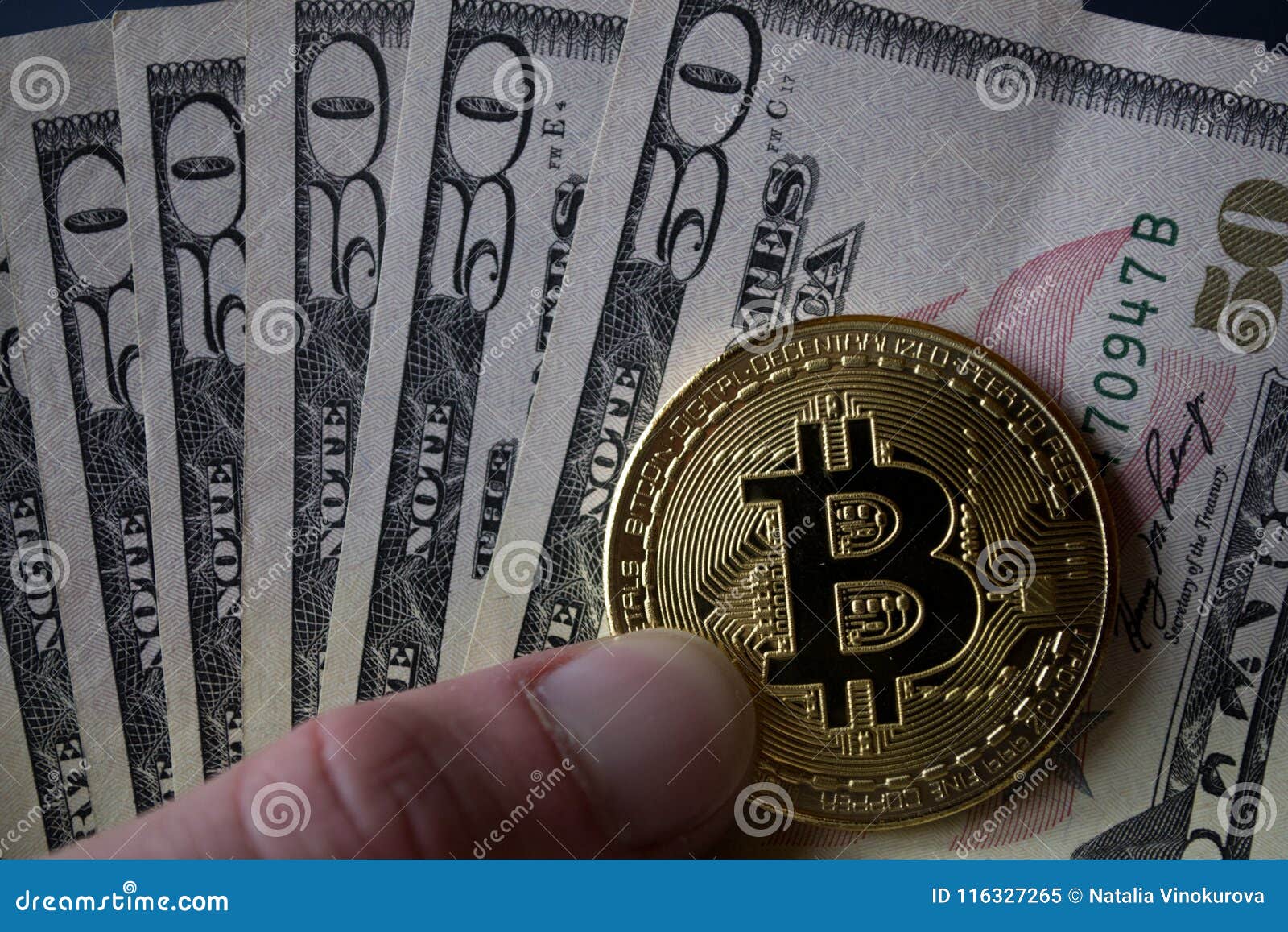Goldenes bitcoin und Dollar in der männlichen Hand auf einem dunkelblauen hölzernen Hintergrund
