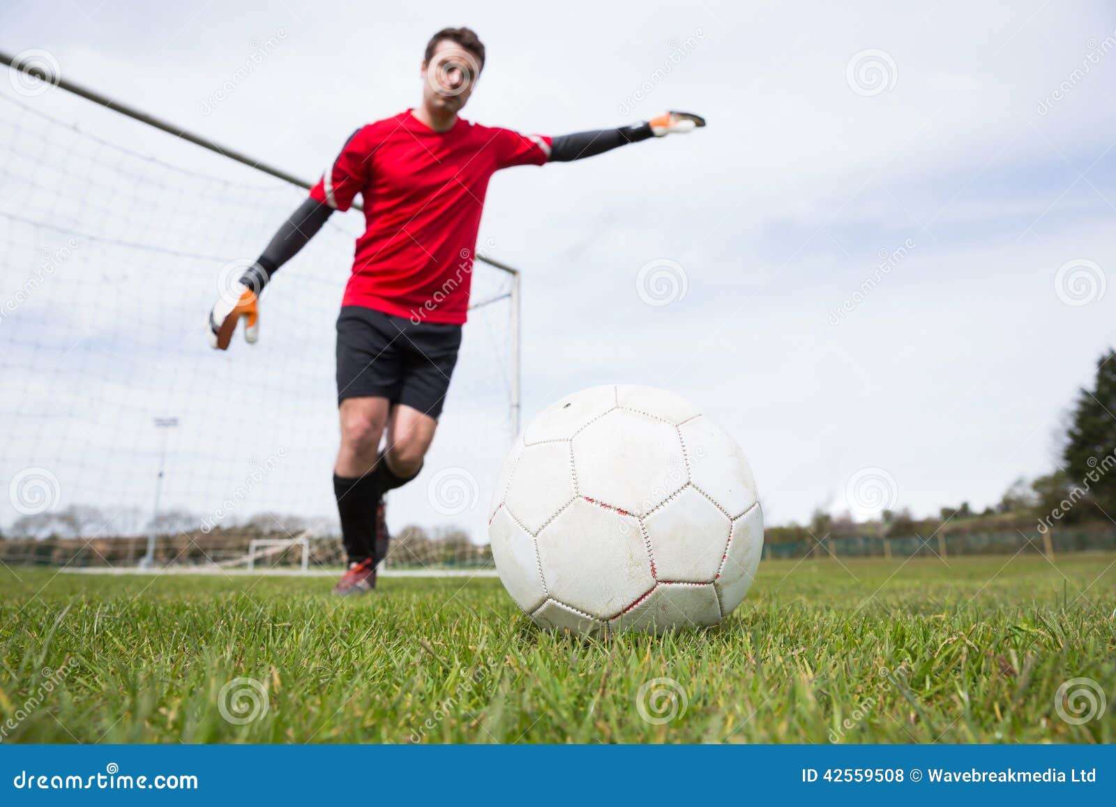 Goleiros na bola de retrocesso vermelha longe do objetivo em um dia claro