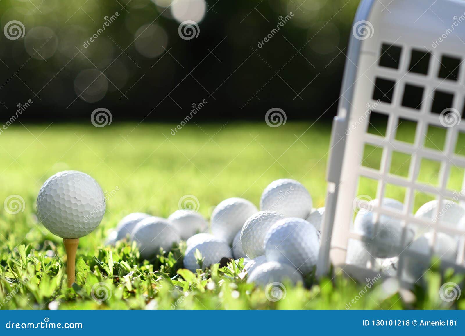 Golf Ball on Tee and Golf Balls in Basket on Green Grass Stock Photo