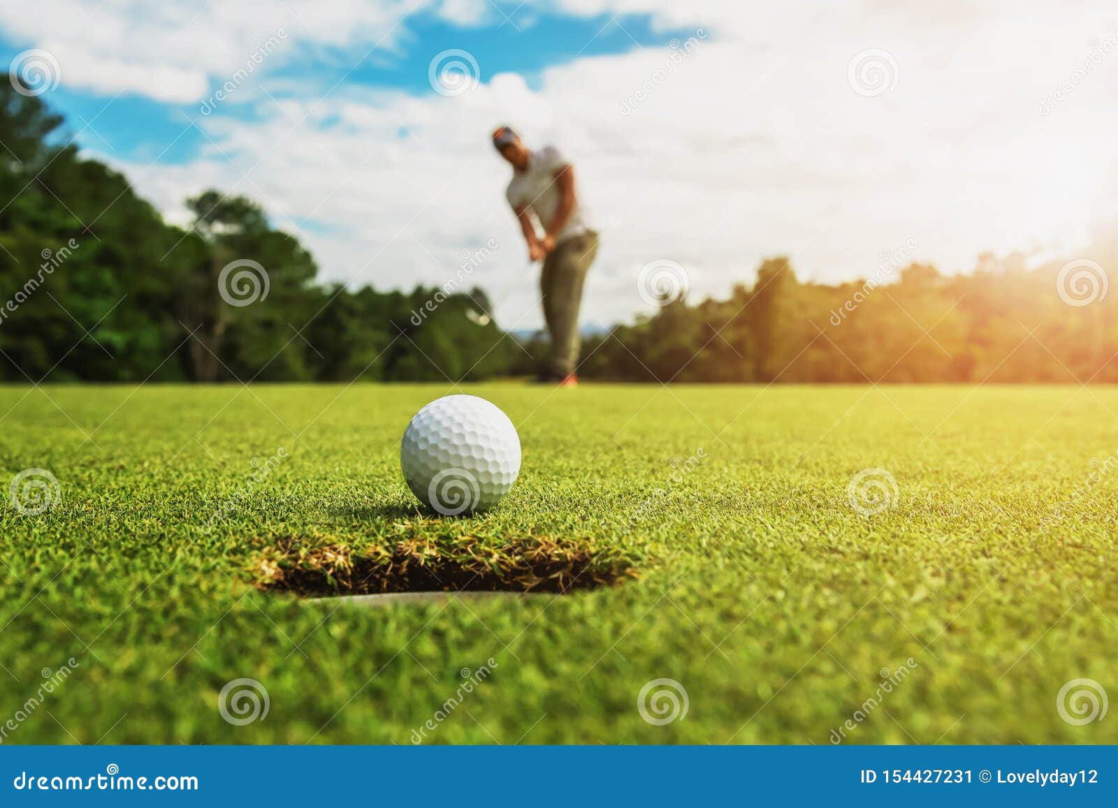 golf player putting golf ball into hole