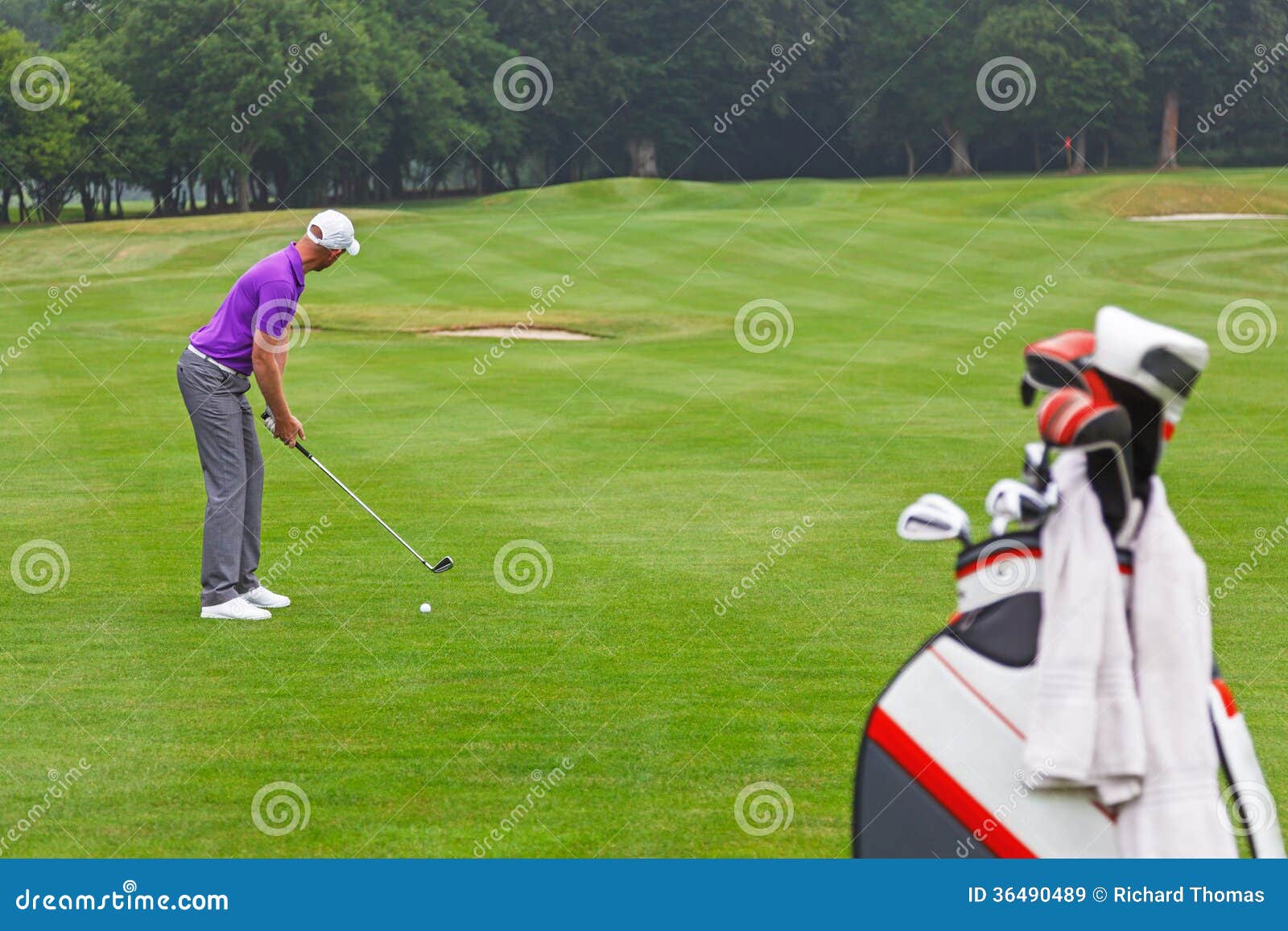 golfer addressing the ball on a par 4 fairway.