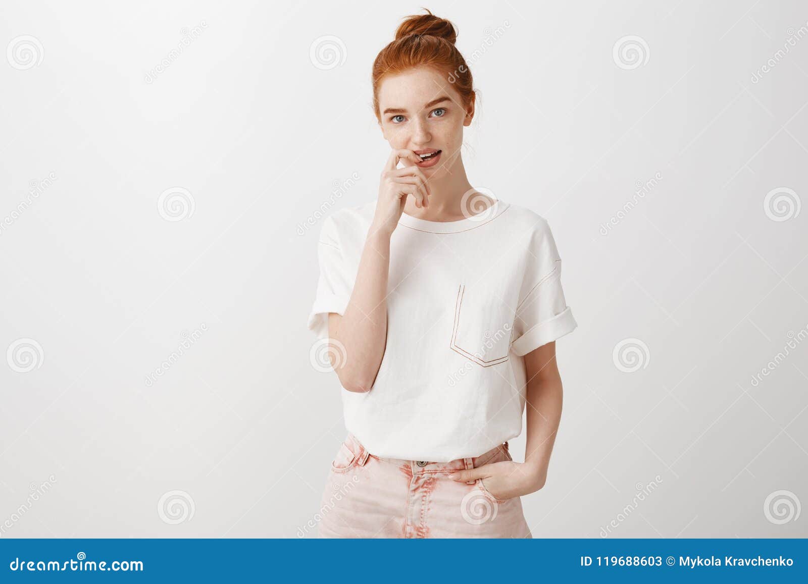 Good-looking Stylish Redhead Female Student with Bun Hairstyle in Trendy T- shirt and Jeans, Holding Finger on Lip and Stock Image - Image of  fashionable, cute: 119688603