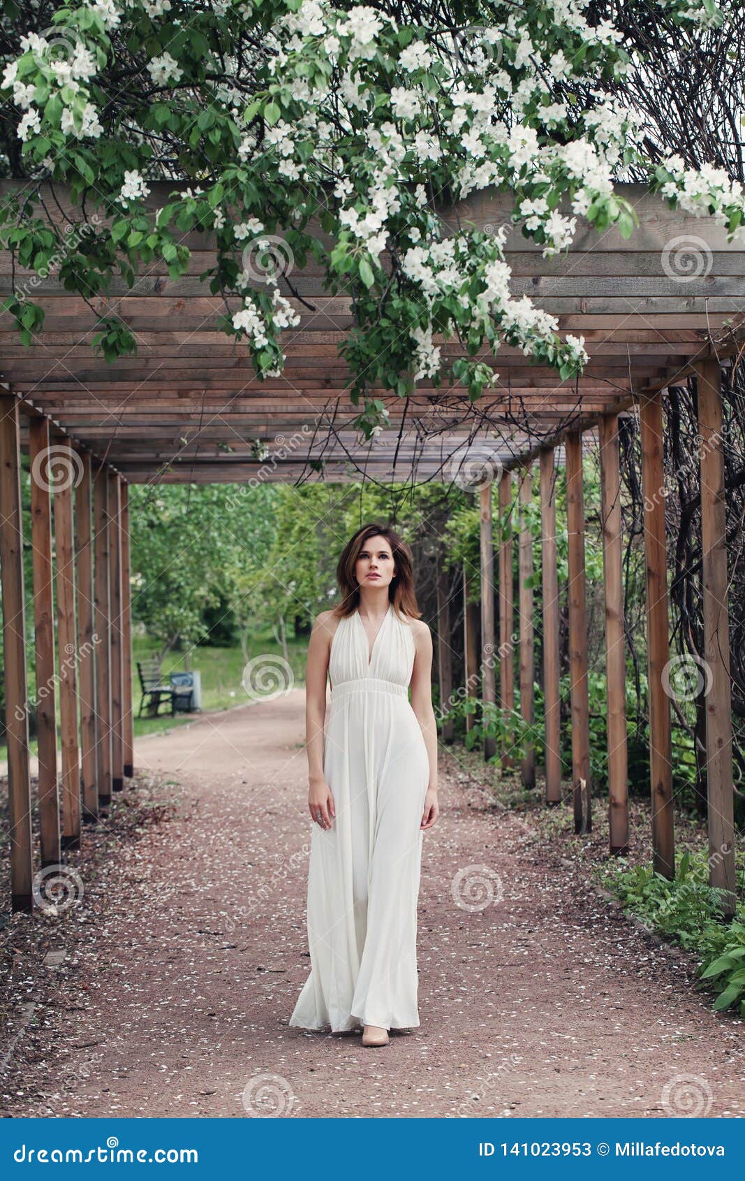 Gorgeous Brunette Woman In White Dress Walking In Spring Garden Outdoor