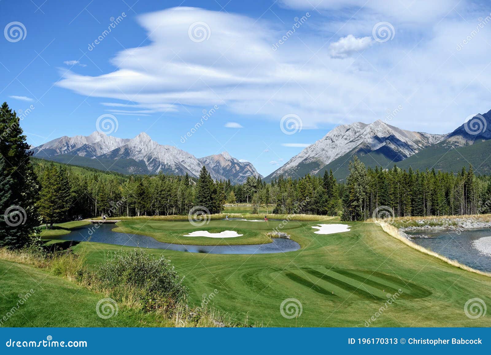 gorgeous par 3 on a golf course surrounded by forest and big mountains in the background, on a beautiful sunny day in kananaskis,