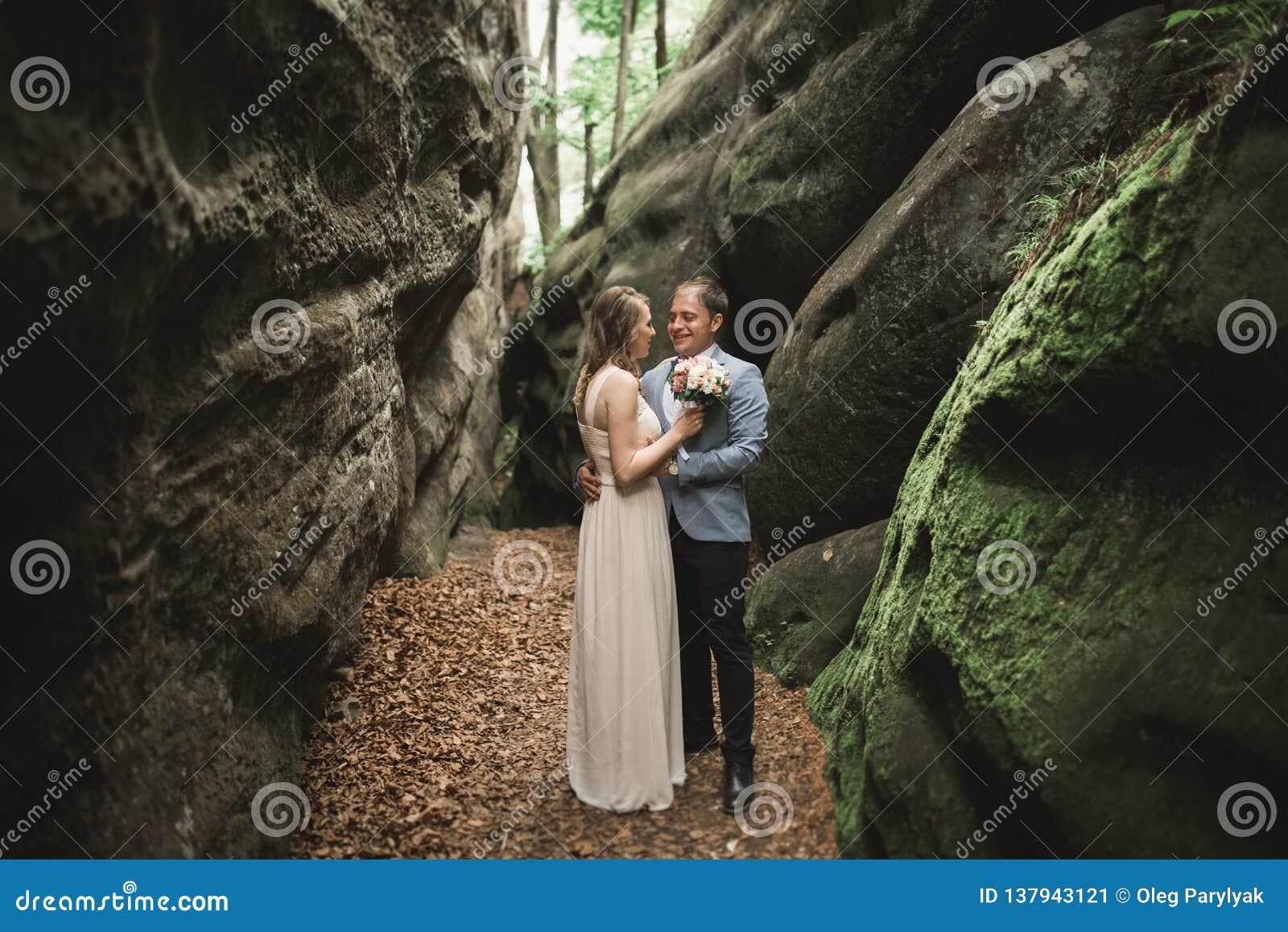 Gorgeous Wedding Couple Kissing And Hugging In Forest With Big Rocks