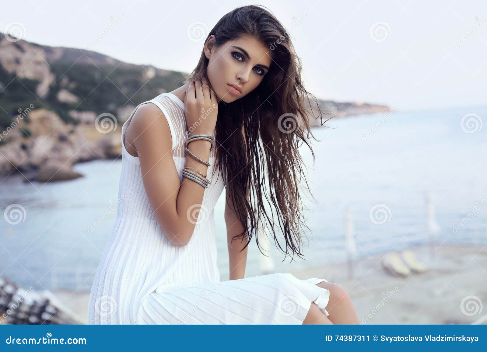 gorgeous woman with dark hair in elegant dress on beach