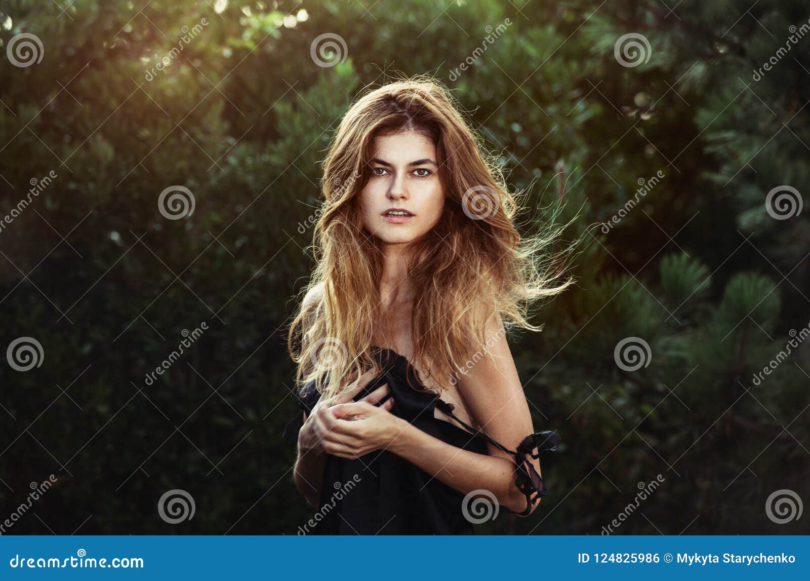 gorgeous woman with natural beauty in forest with windy long healthy hair and natural makeup