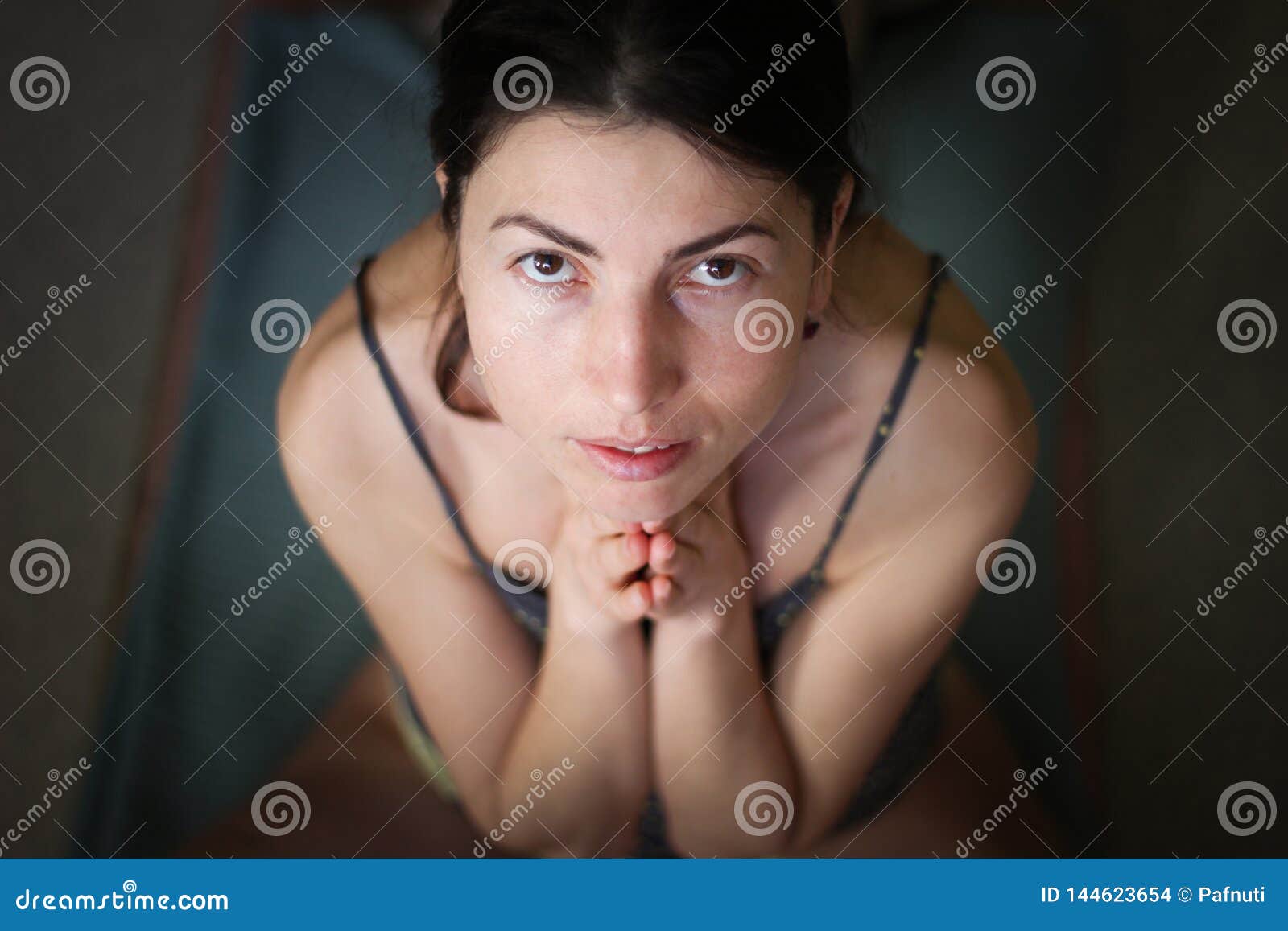 gorgeous young europian female on dark background, holding hands in namaste or prayer, keeping eyes open, while practising yoga