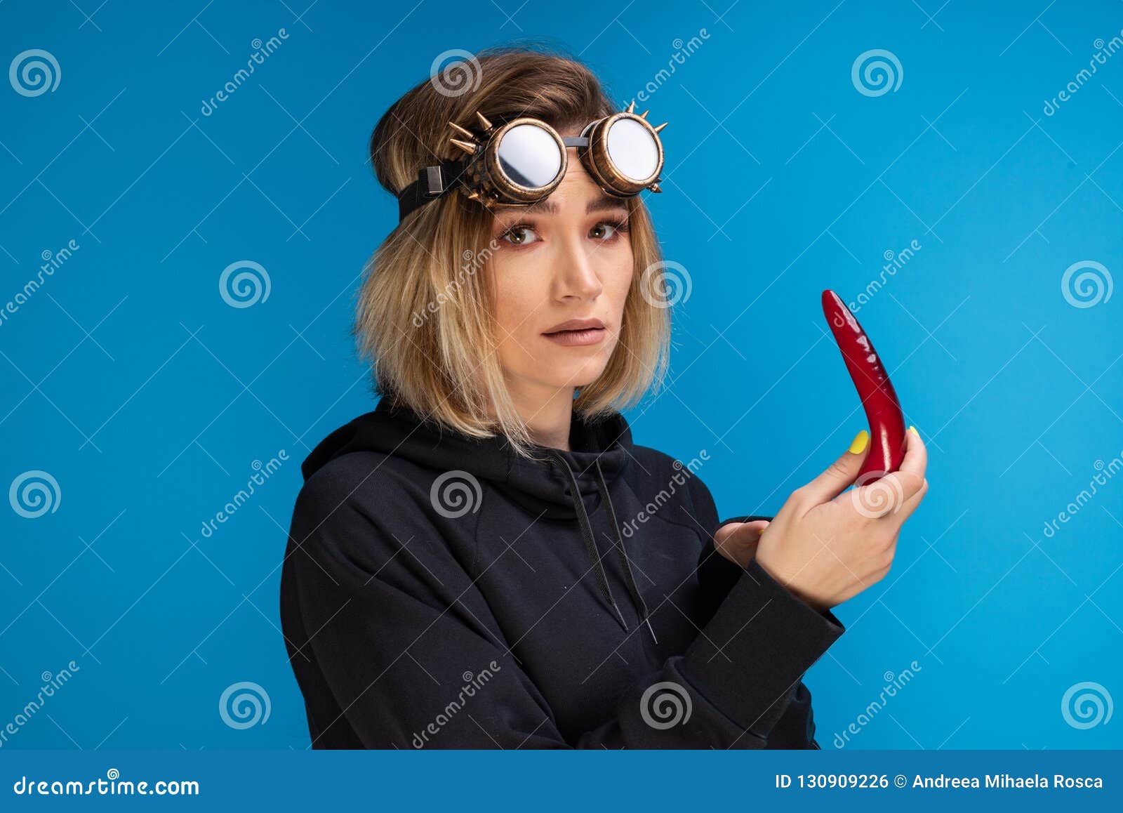 Goth Girl Wearing Steam Punk Glasses and Dark Hoodie is Looking Confused at  a Red Chilli Pepper Stock Photo - Image of adult, beautiful: 130909226