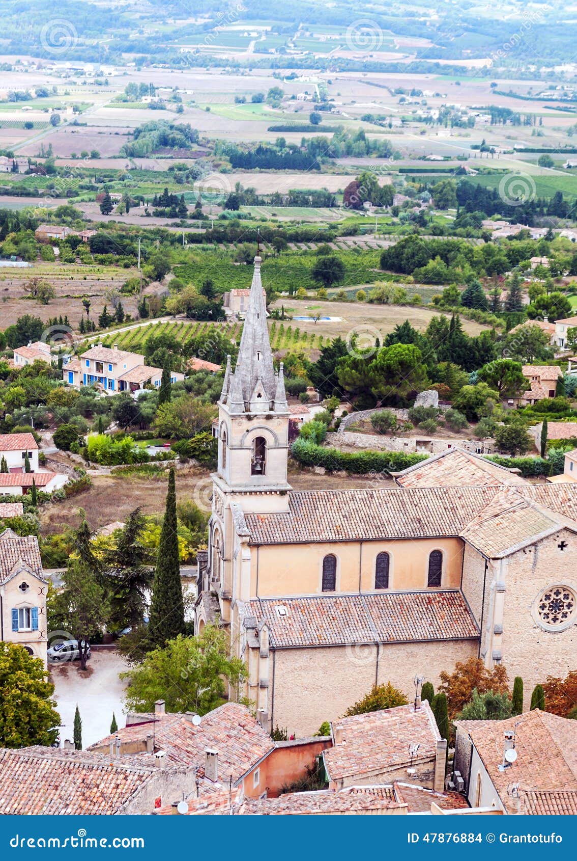 Gothic churchin a rural village. Some houses in a rural village in France with gothic church, surrounded by forest and mountains on a cloudy day. ItÂ´s a vertical picture