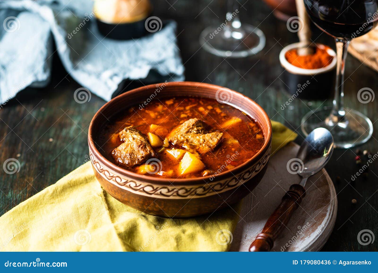 goulash or stew in copper pan with spoon on rustic kitchen table. eintopf, chili con carne. traditional hungarian dish. homemade
