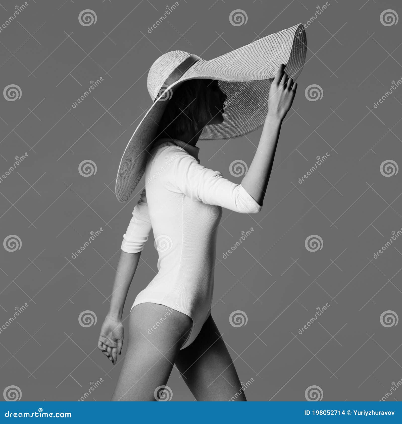 a graceful woman posing with a large wide-brimmed hat.