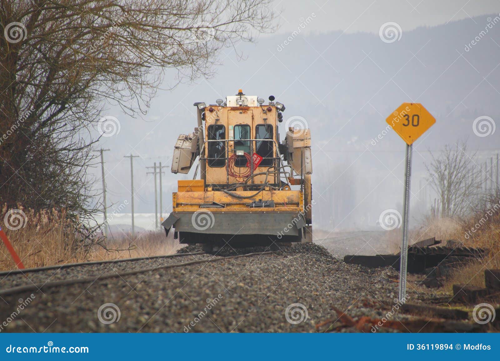 machine is used to level gravel alongside a railway track.