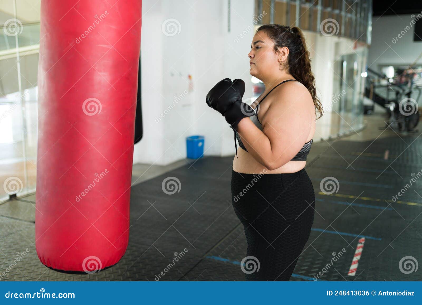 Mujer atractiva con guantes de boxeo listos para hacer ejercicio en el  gimnasio