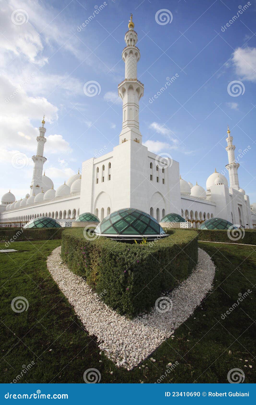 Grand mosque outside. Vertical shot looking at the spires of the Grand Mosque in Abu Dhabi. Three towers balance the picture with green grass in foreground and blue skies and clouds in background