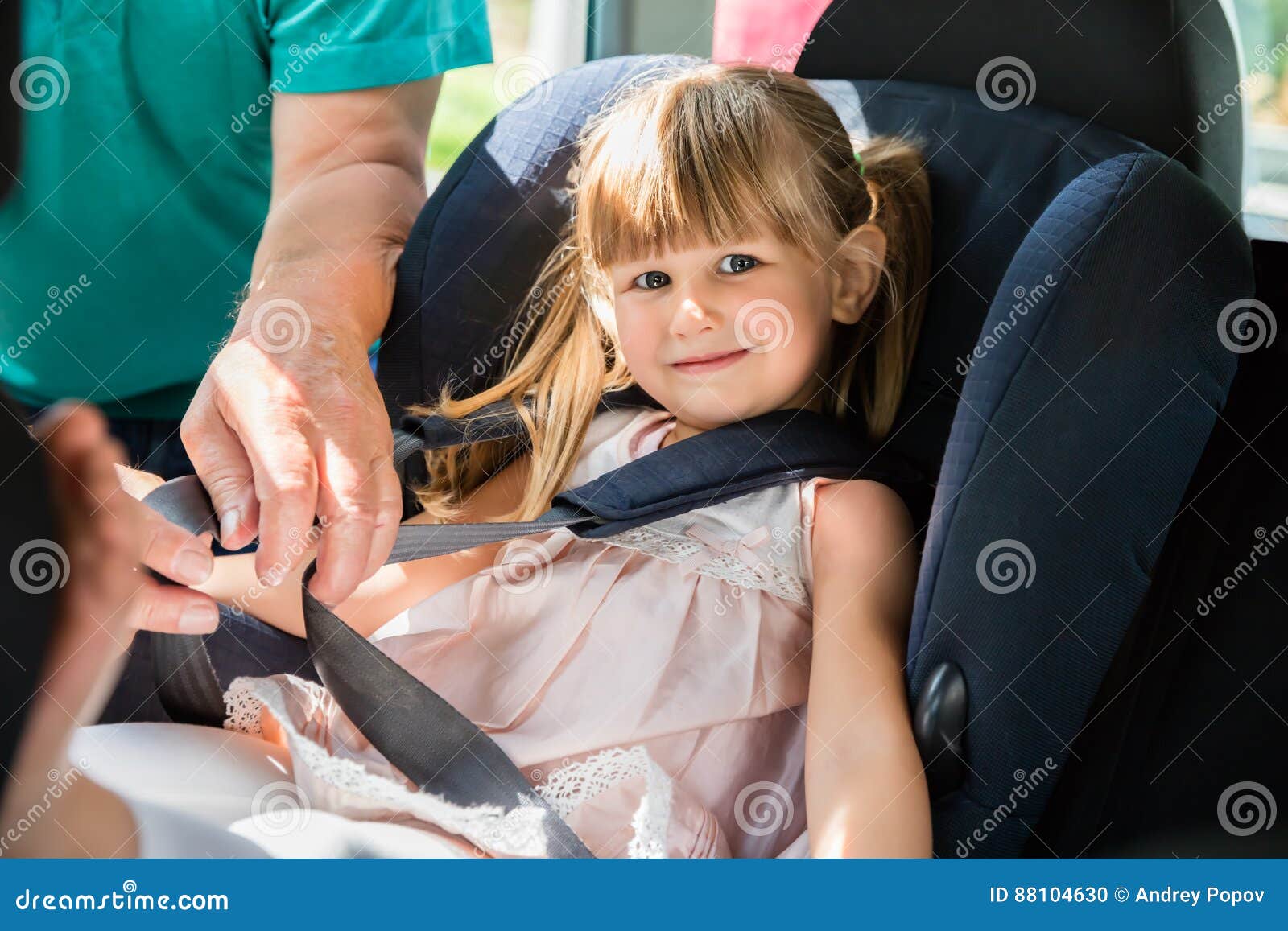 grandfather buckling up on granddaughter in car safety seat