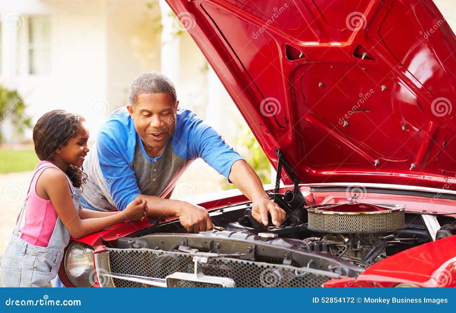grandfather and granddaughter working on restored car