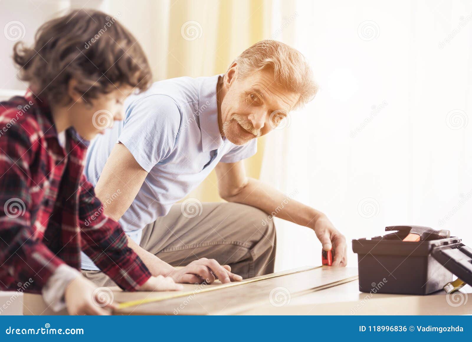 Grandfather And Grandson Are Measuring Table With