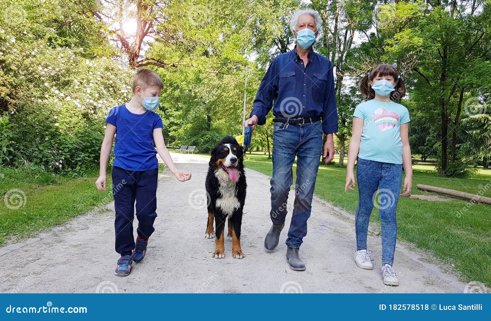 a grandfather and grandson are walking in the park with the dog during coronavirus pandemia