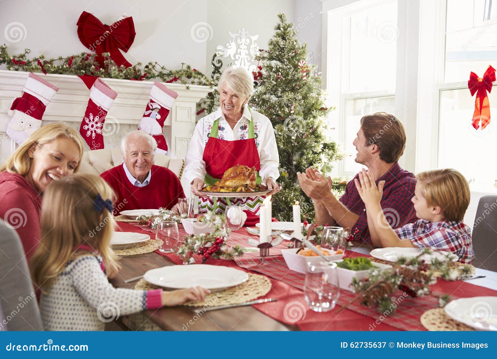 grandmother bringing out turkey at family christmas meal