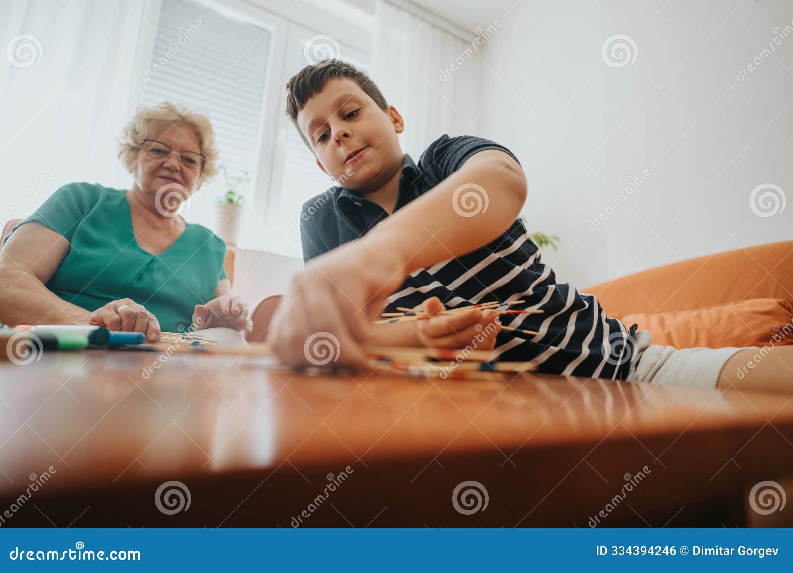 grandmother and grandson playing pick-up sticks on a sunny afternoon