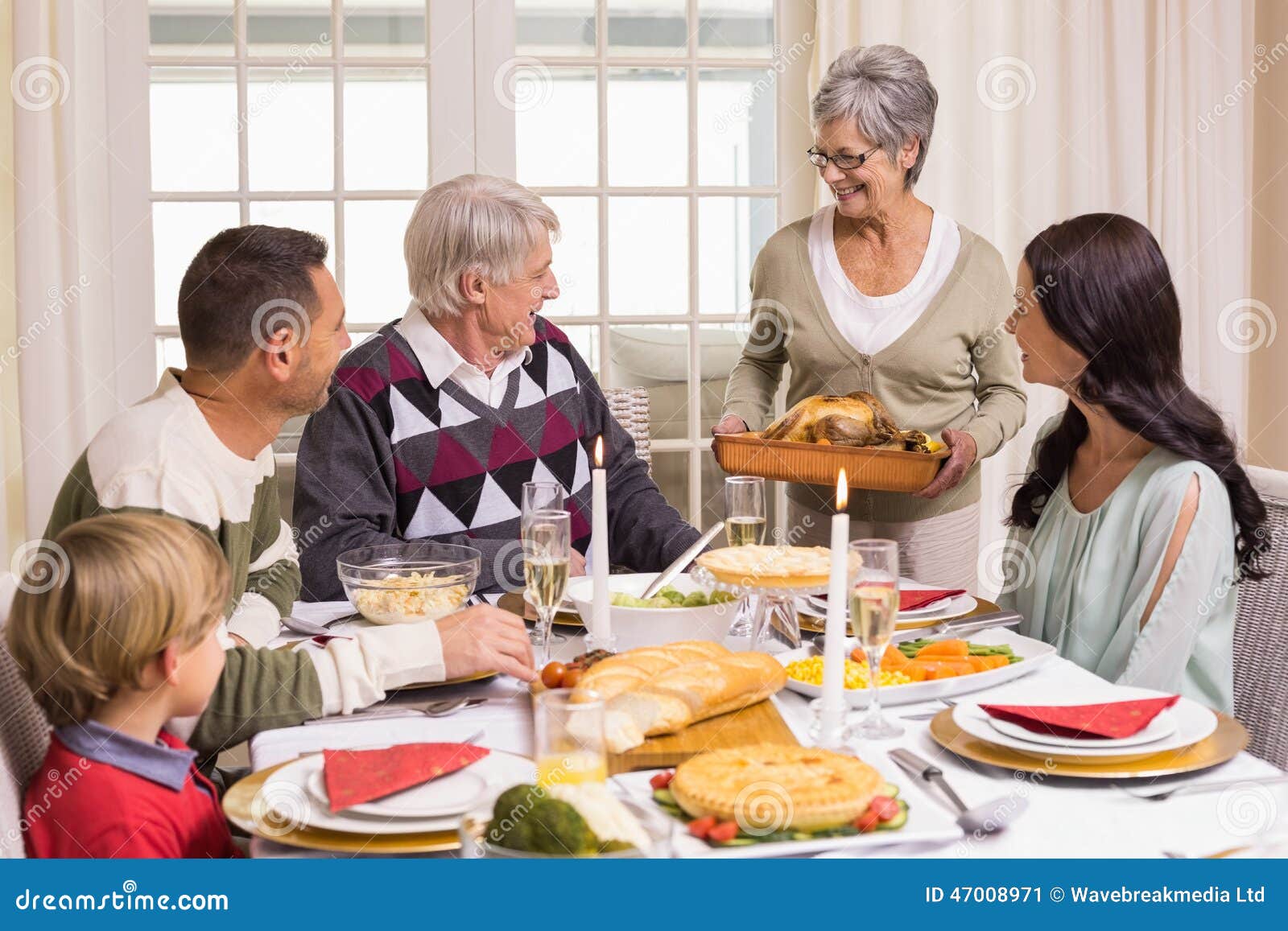 Grandmother Holding Turkey Roast with Family at Dining Table Stock ...