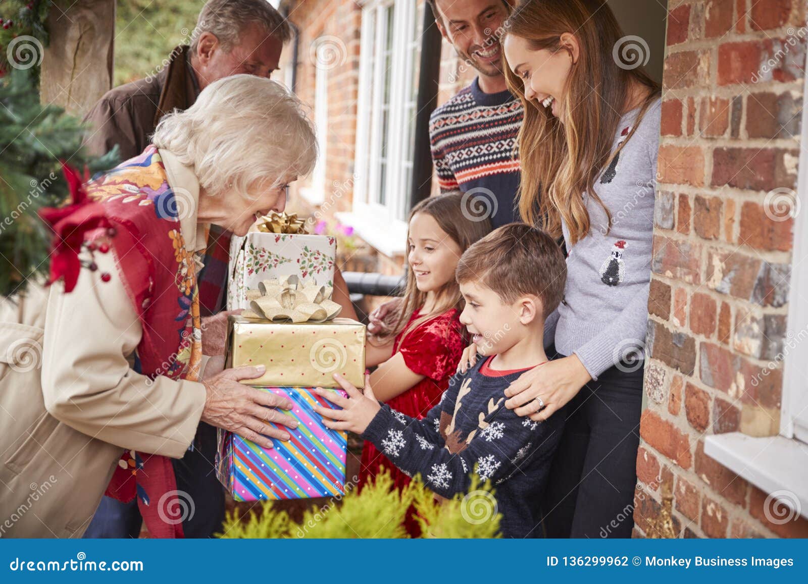 grandparents being greeted by family as they arrive for visit on christmas day with gifts