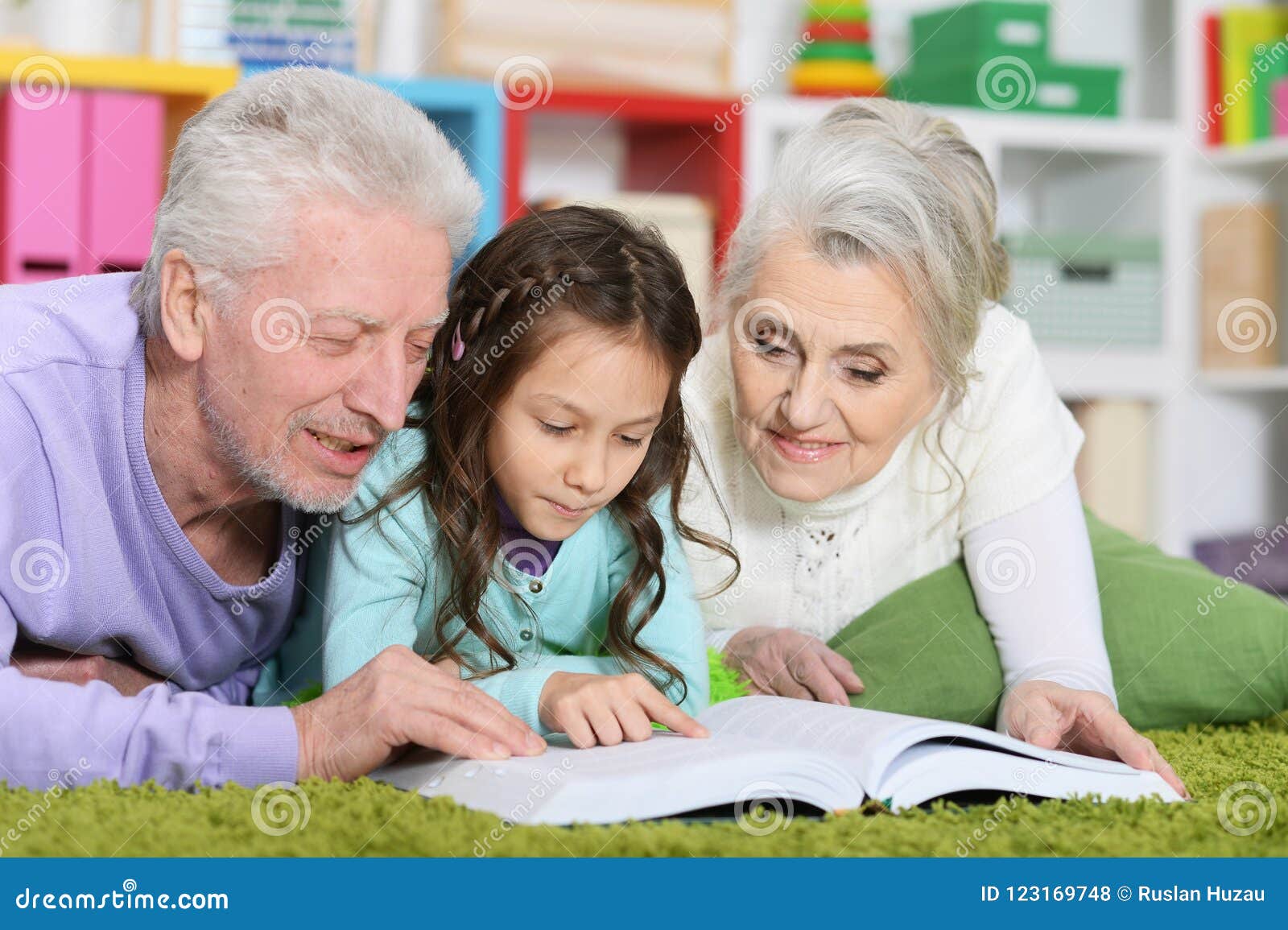 grandparents reading book with little granddaughter
