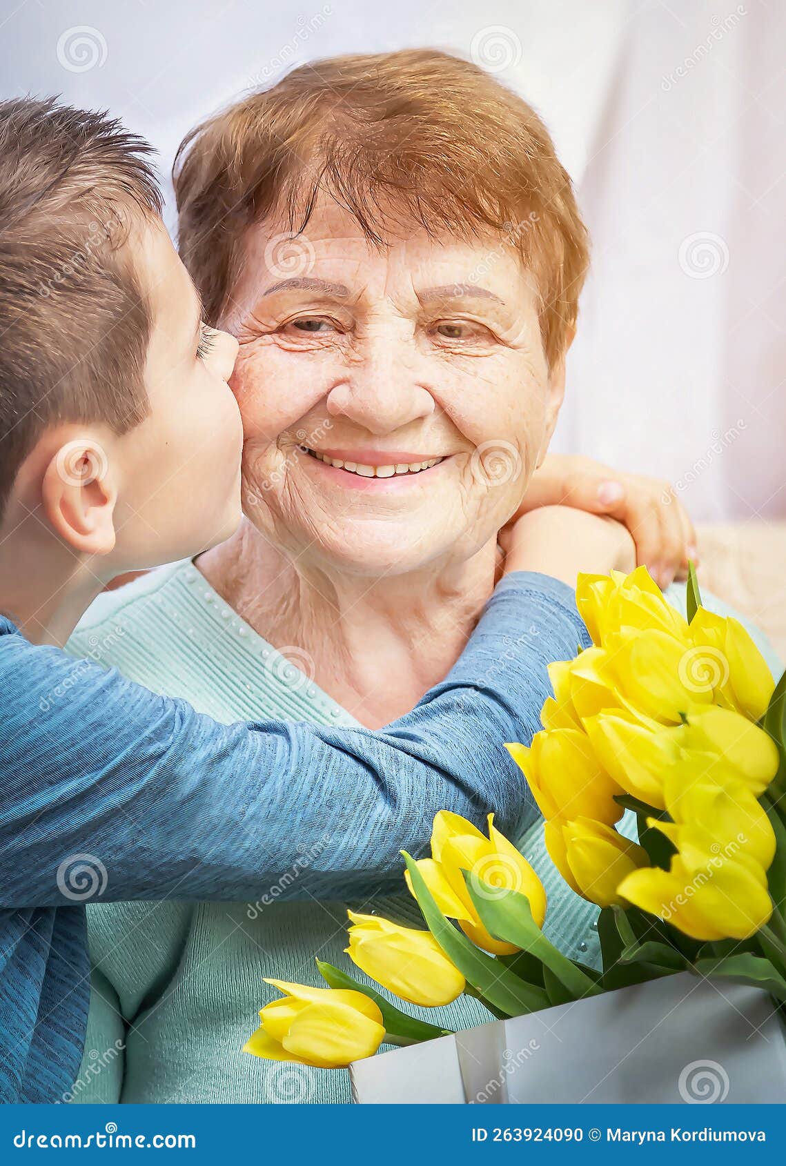 grandson congratulates grandma on holiday. grandmother has bunch of yellow flowers. kindness to senior woman.