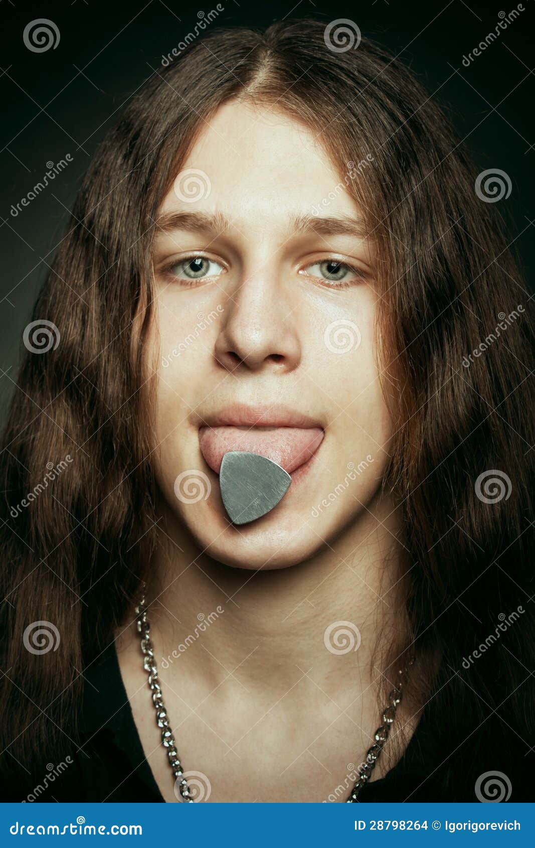 Jonge grappige zwaar metaalgitarist met bemiddelaar op zijn tong