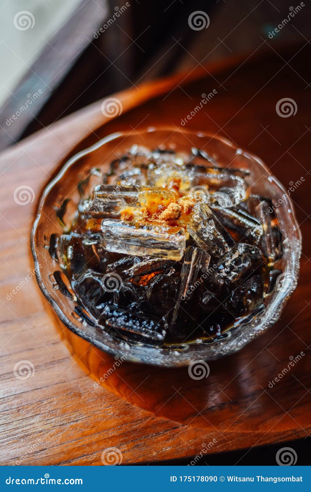 grass jelly in syrup with ice cubes leaf jelly in bowl on wood table, thai dessert grass jelly, chao koui