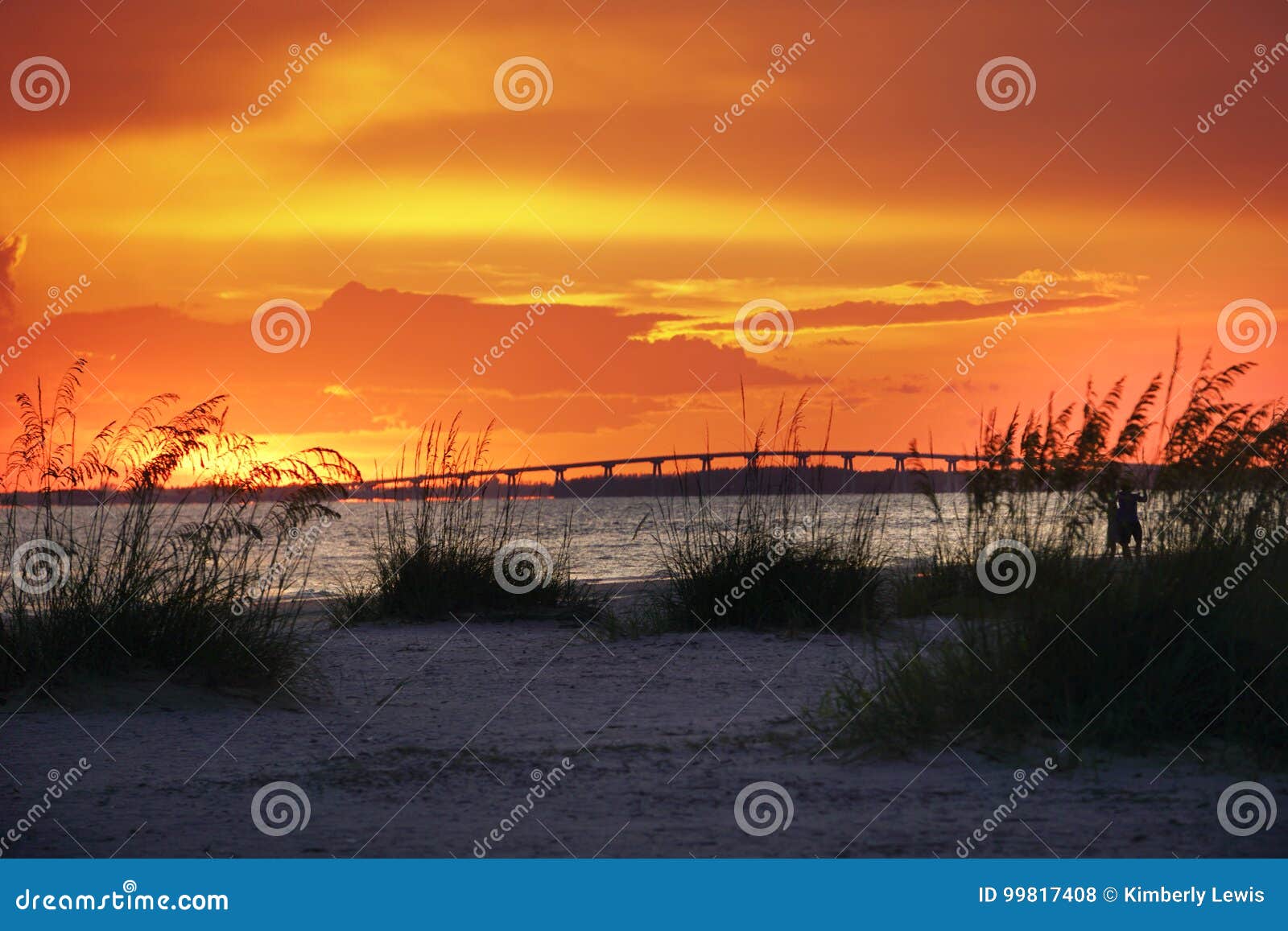 the glowing orange sunset over the bridge that leads to sanibel and captiva islands from ft.myers beach, florida.