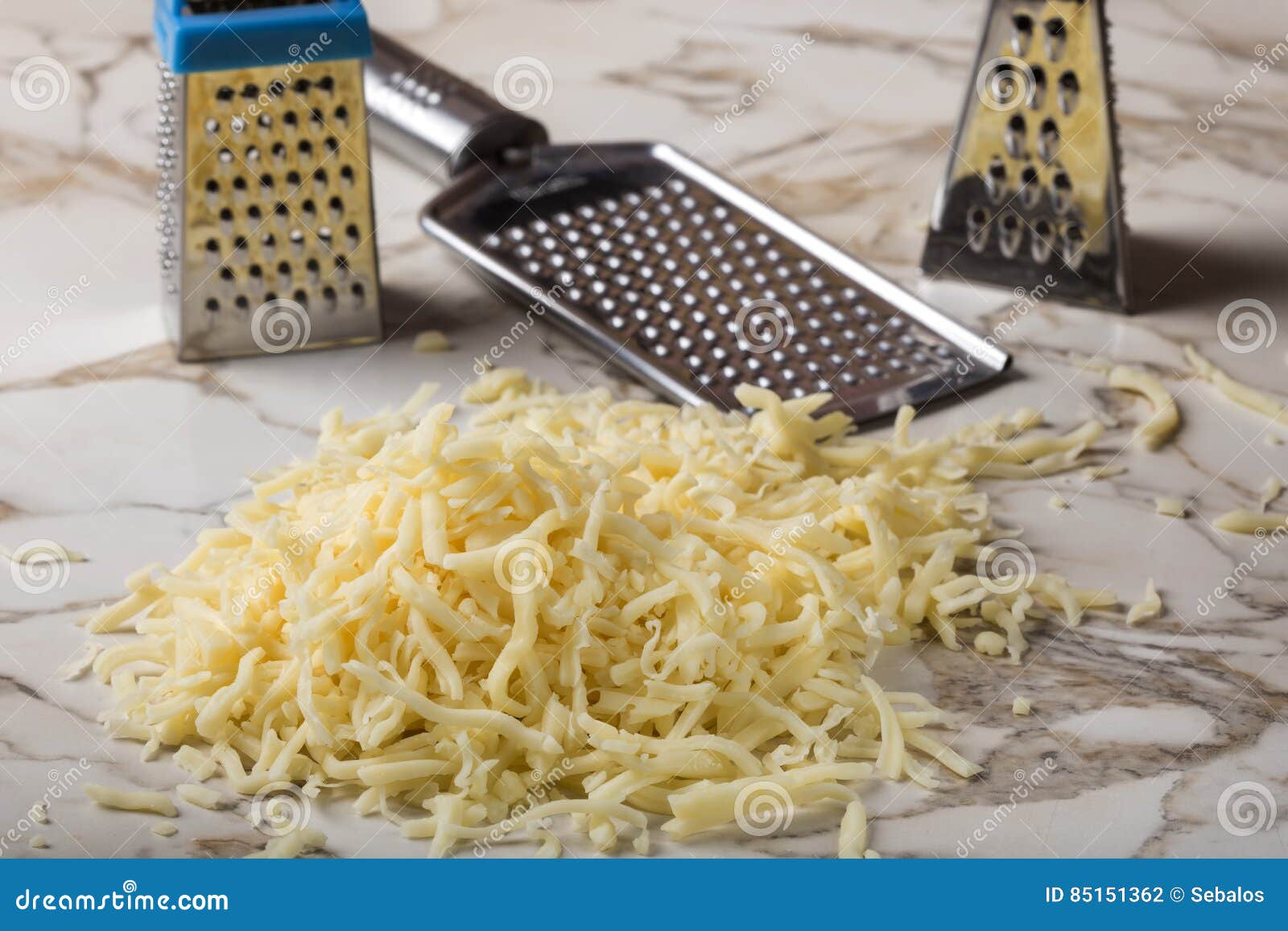 Grated Mix Cheese and Three Stainless Steal Graters in Background Stock