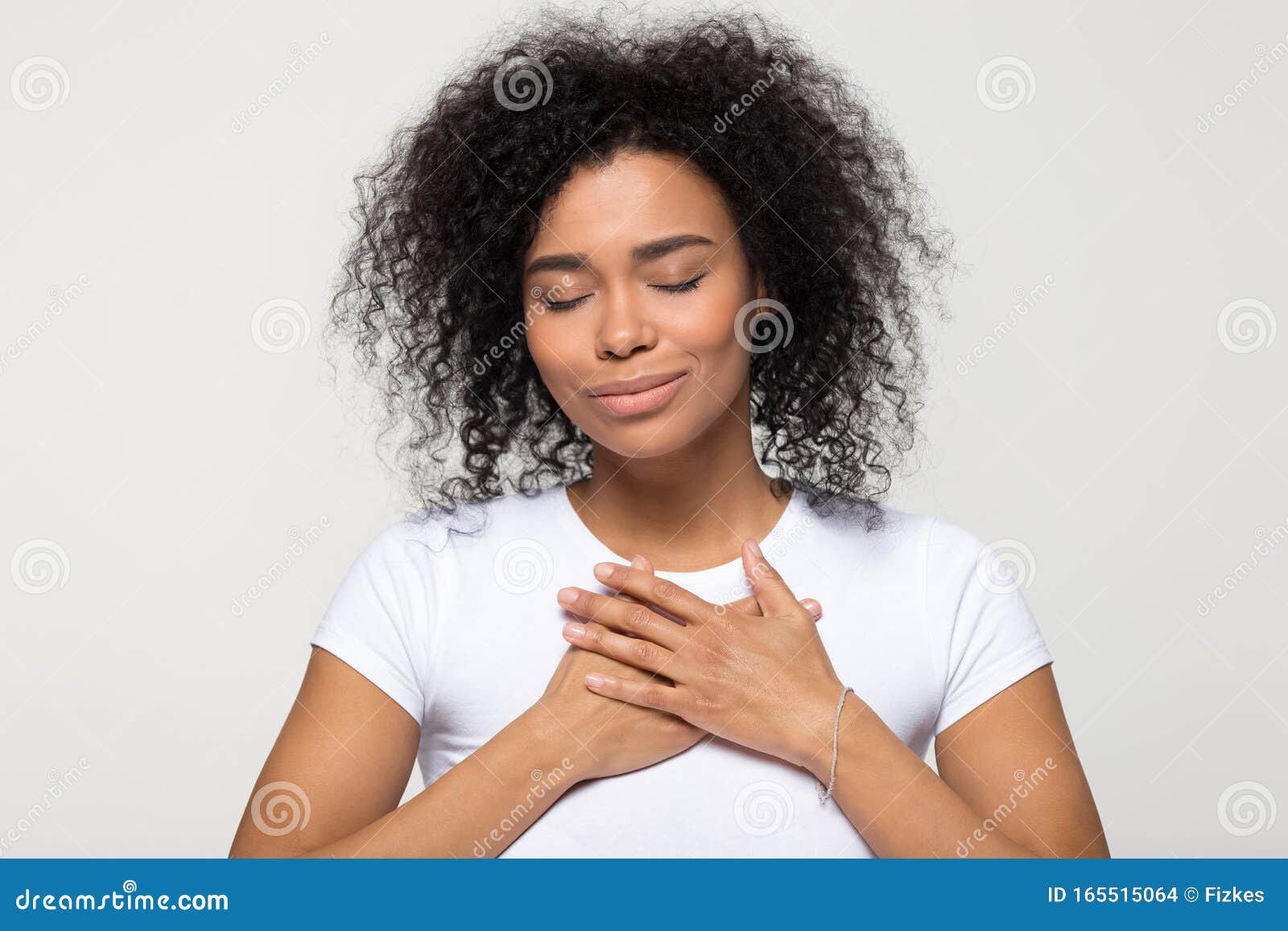 grateful hopeful african american woman holding hands on chest