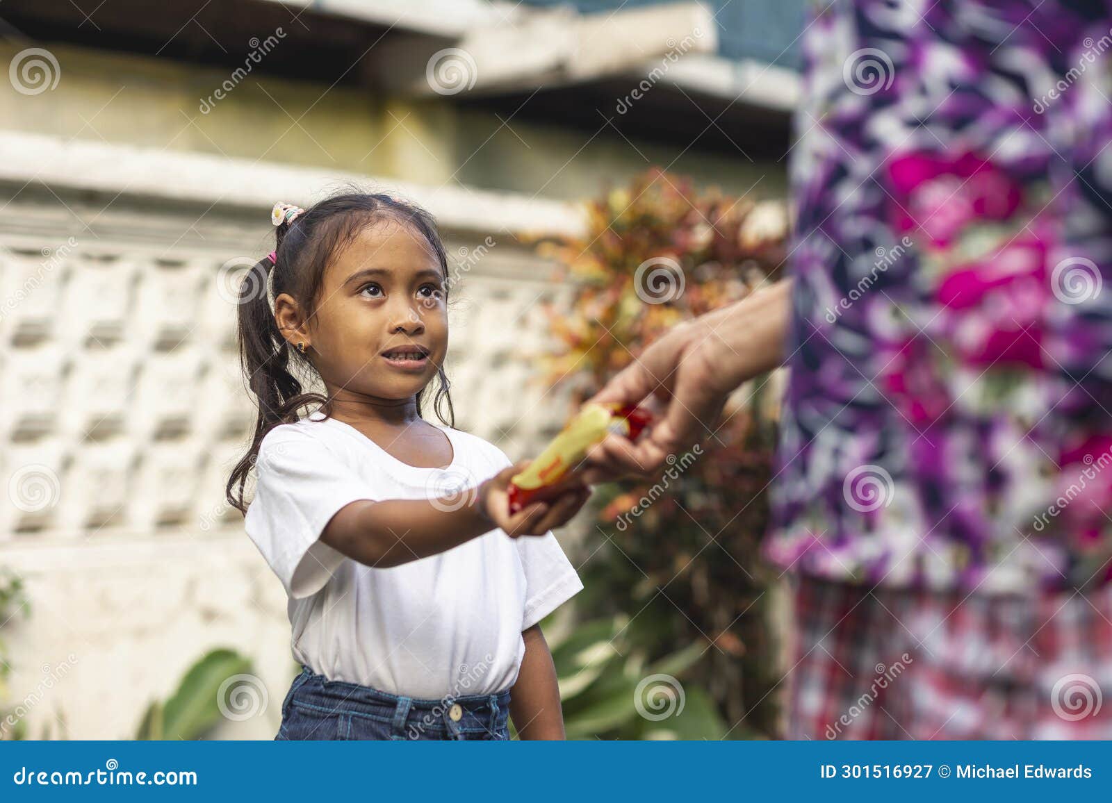 a grateful young girl saying thank you after given a pack of biscuits by her grandmother. outdoor scene