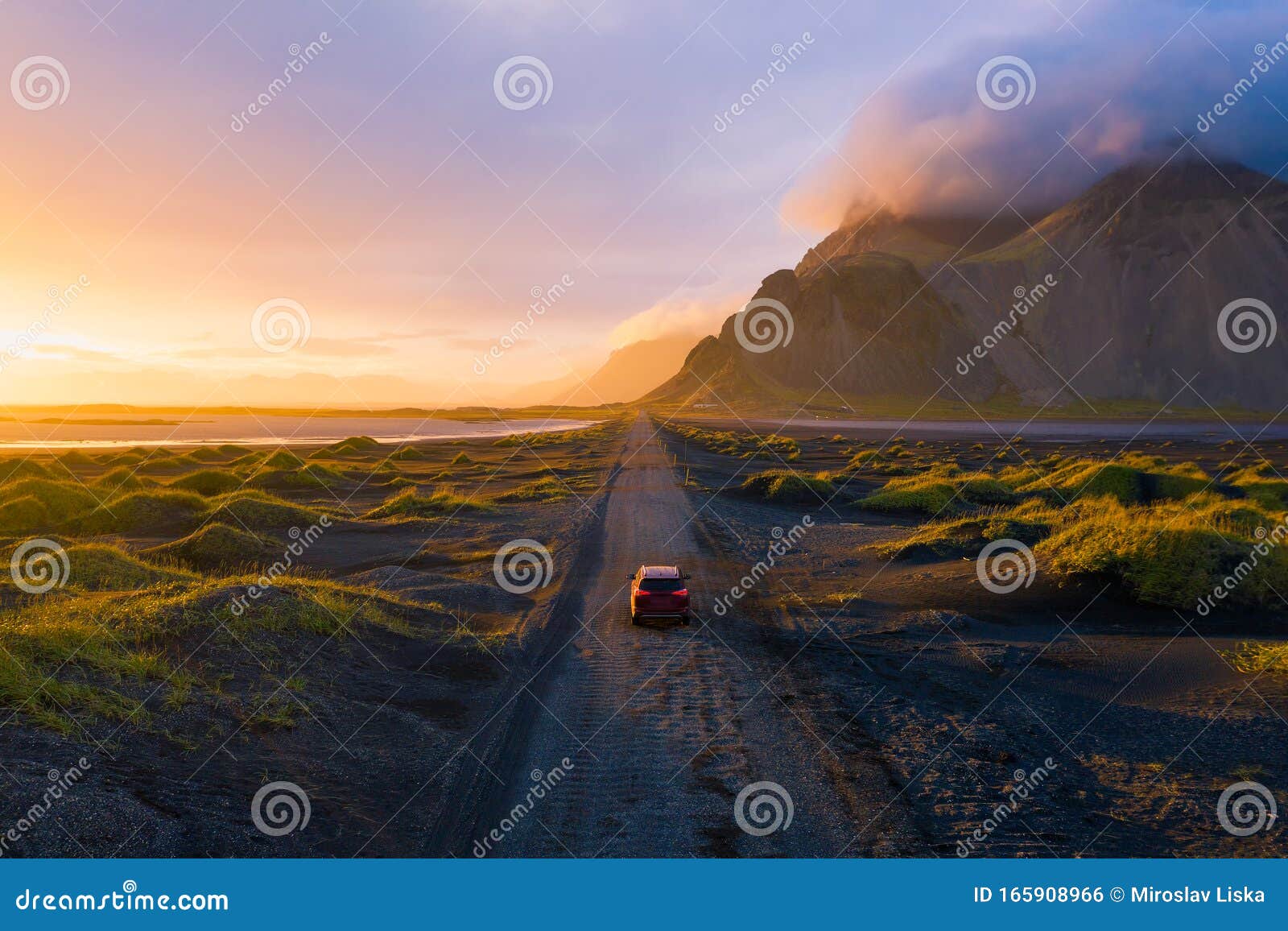 gravel road at sunset with vestrahorn mountain and a car driving, iceland