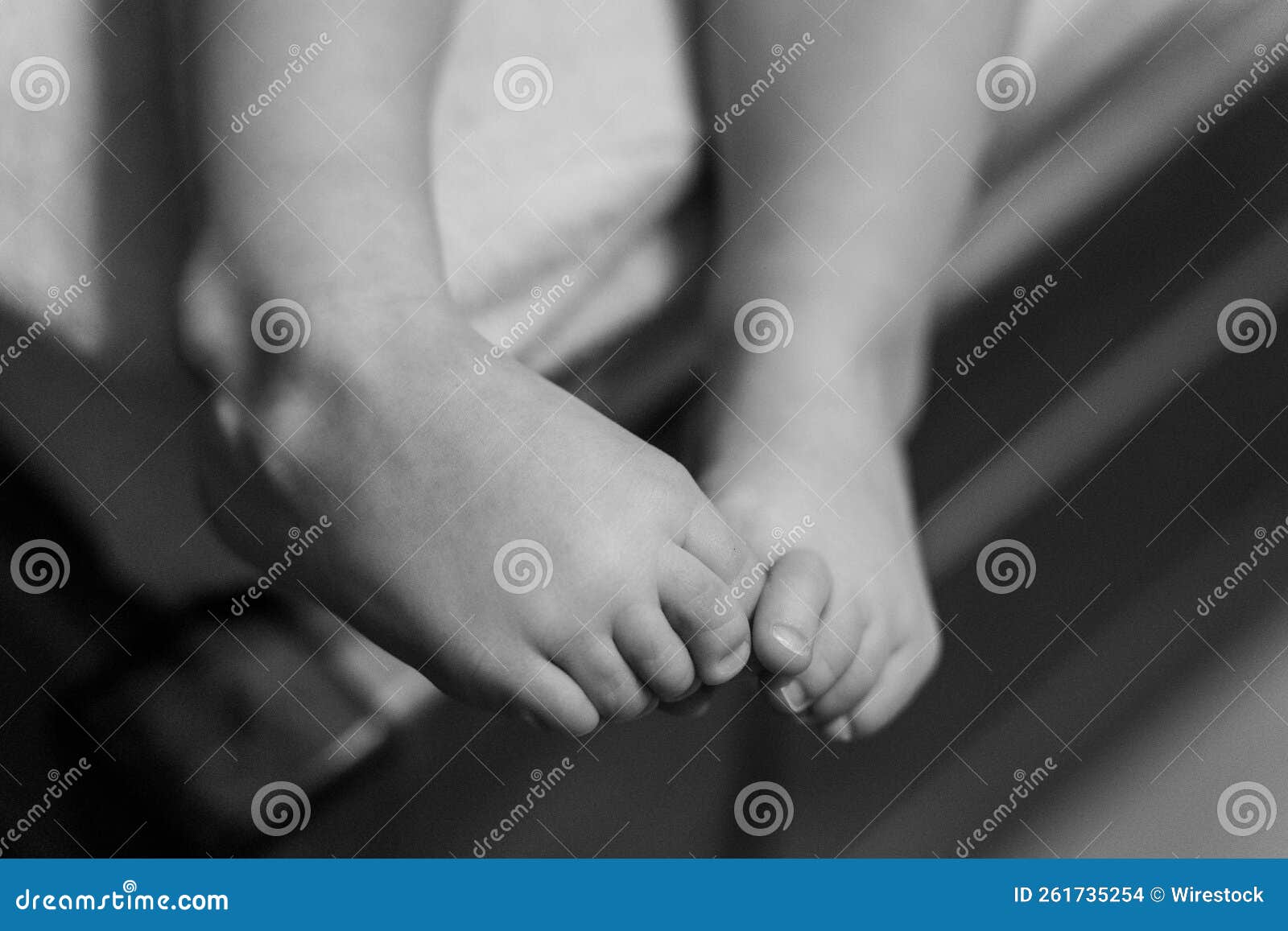 Grayscale Shot of a Child S Legs Play with Each Other Stock Photo