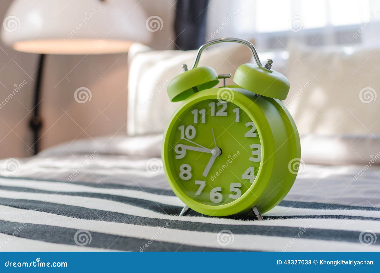 Green alarm clock on bed stock photo. Image of green 48327038