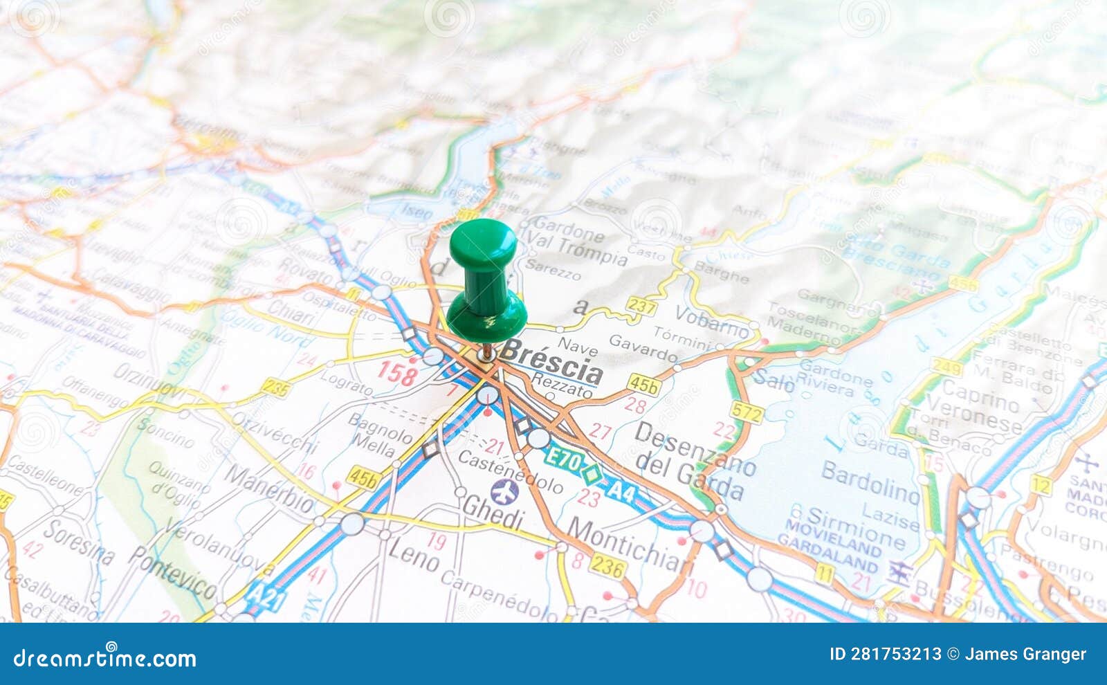 a green board pin stuck in brescia on a map of italy