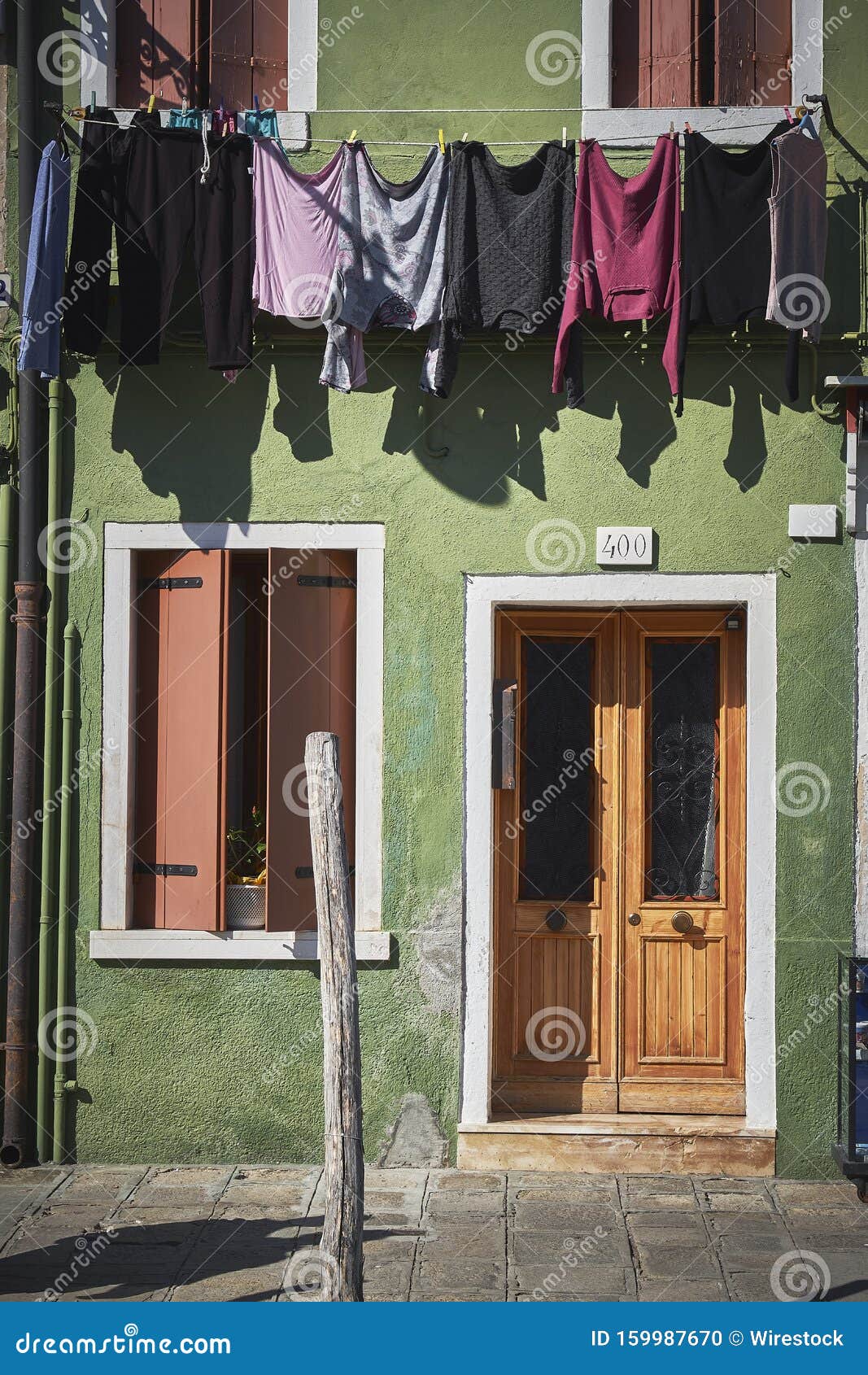 A Green Building with Wooden Doors and Windows and Colorful Clothes ...