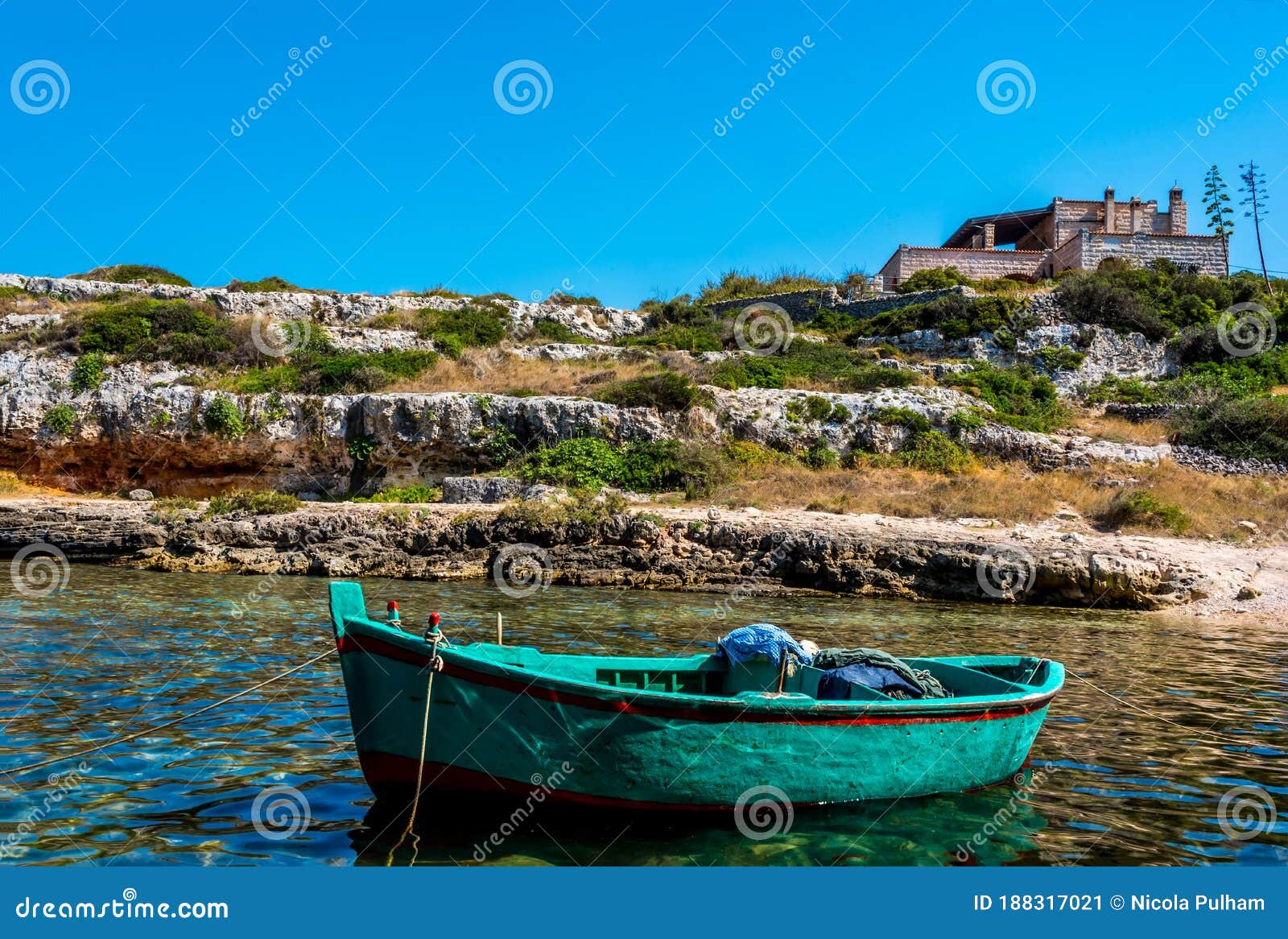 a green fishing boat moored in an inlet near polignano a mare, puglia, italy