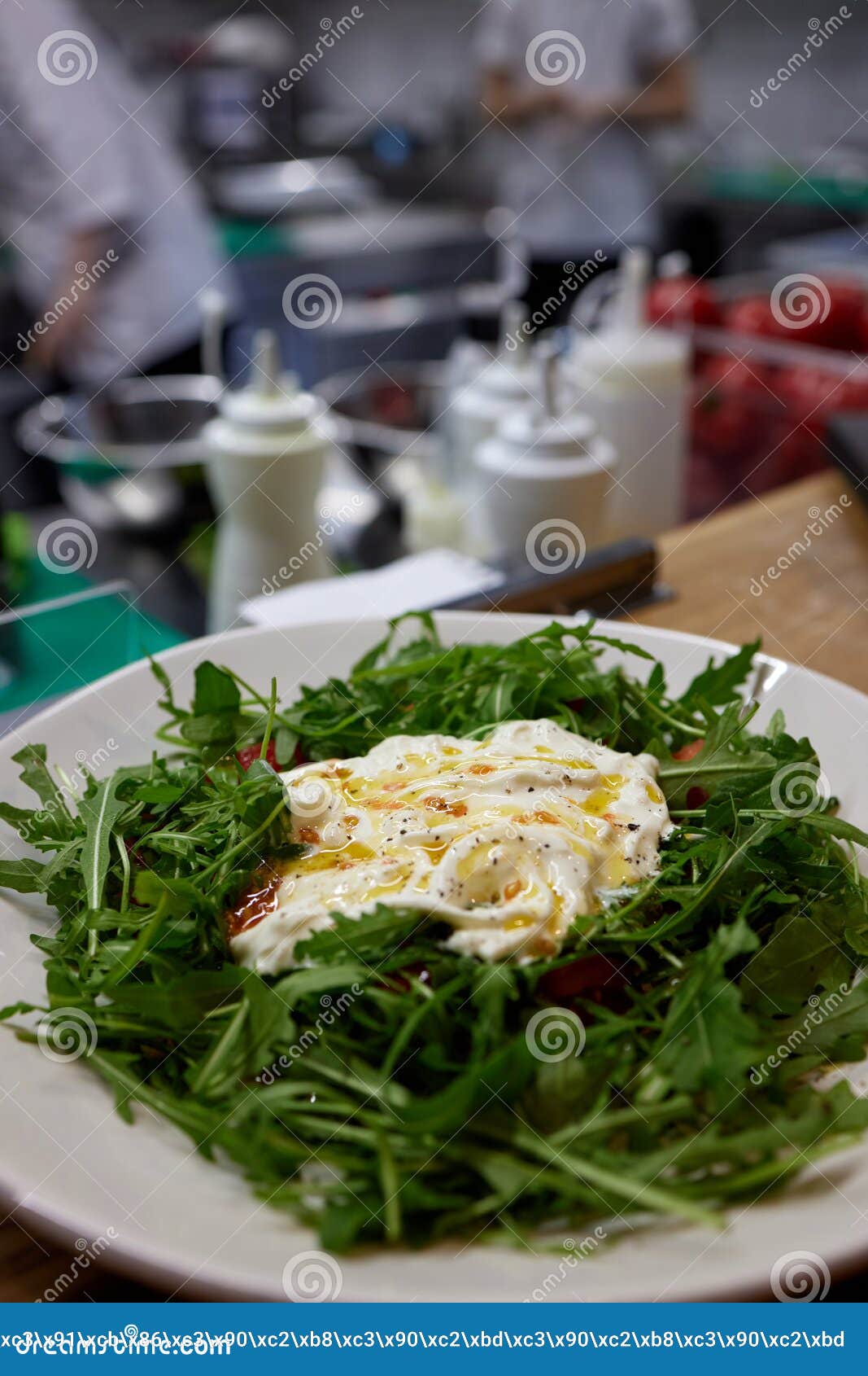 a green french bistro style salad with poached egg and chives on a white plate and table setting.