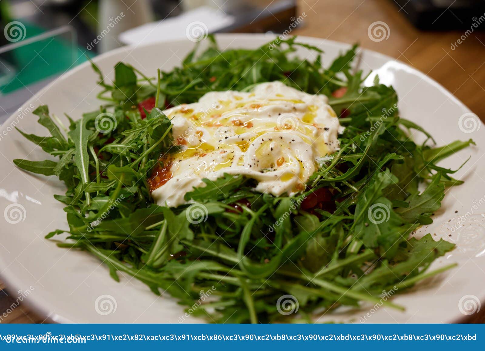 a green french bistro style salad with poached egg and chives on a white plate and table setting.