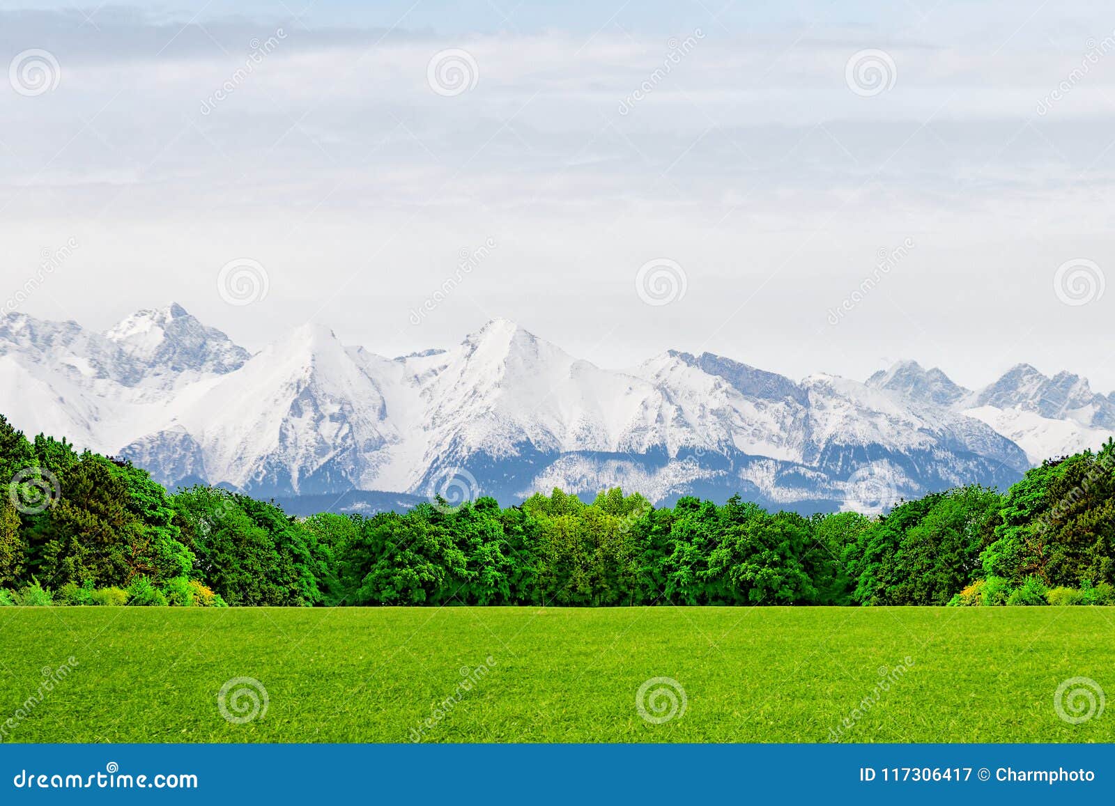 A Green Glade At The Foot Of Snow Capped Mountain Peaks A Miracle Of