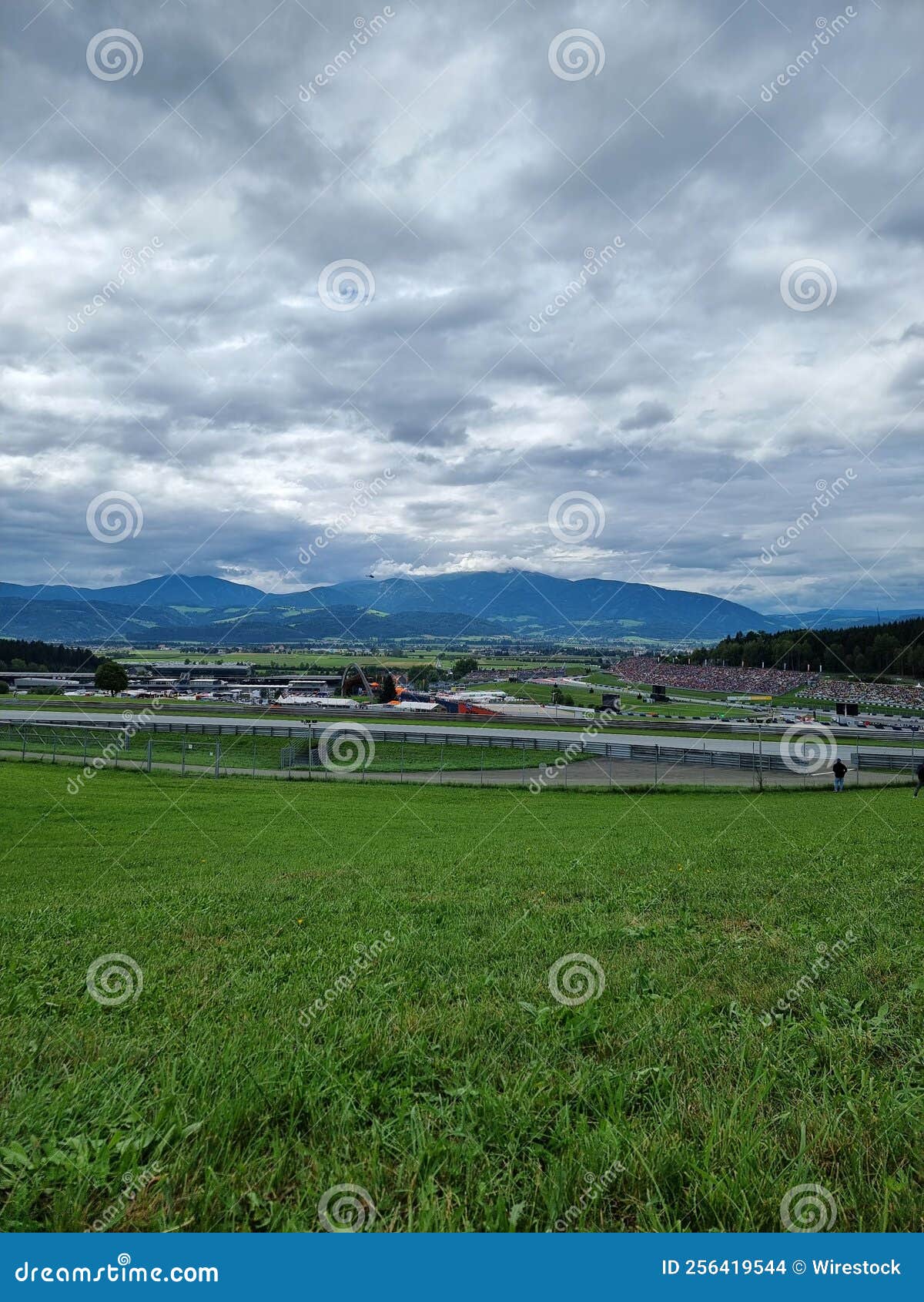 green lawn field and cith buildings in a distance under dramatic cloudy sky on the horizon